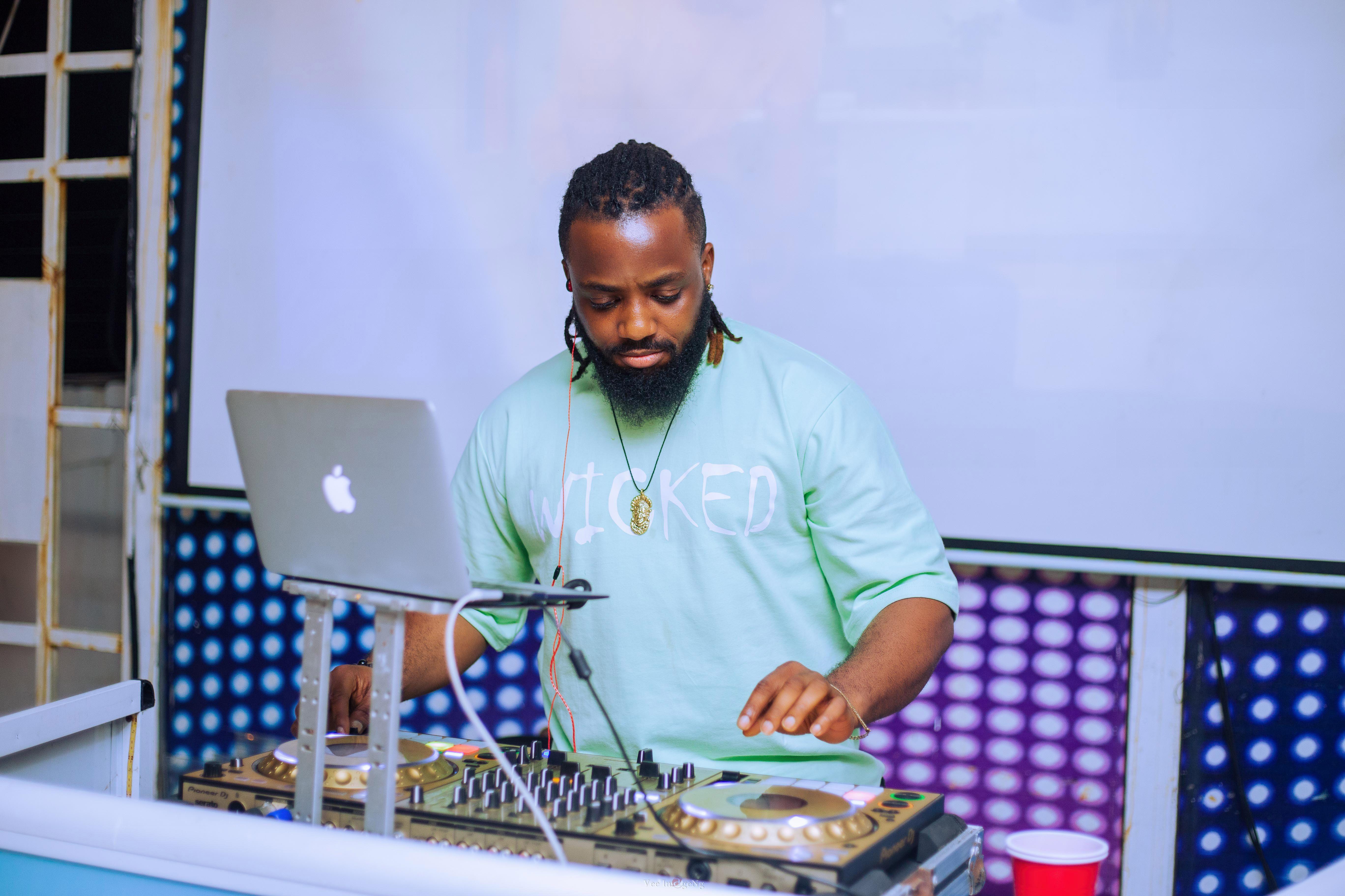 DJ performing with mixer and laptop at an indoor music event in Lagos, Nigeria.