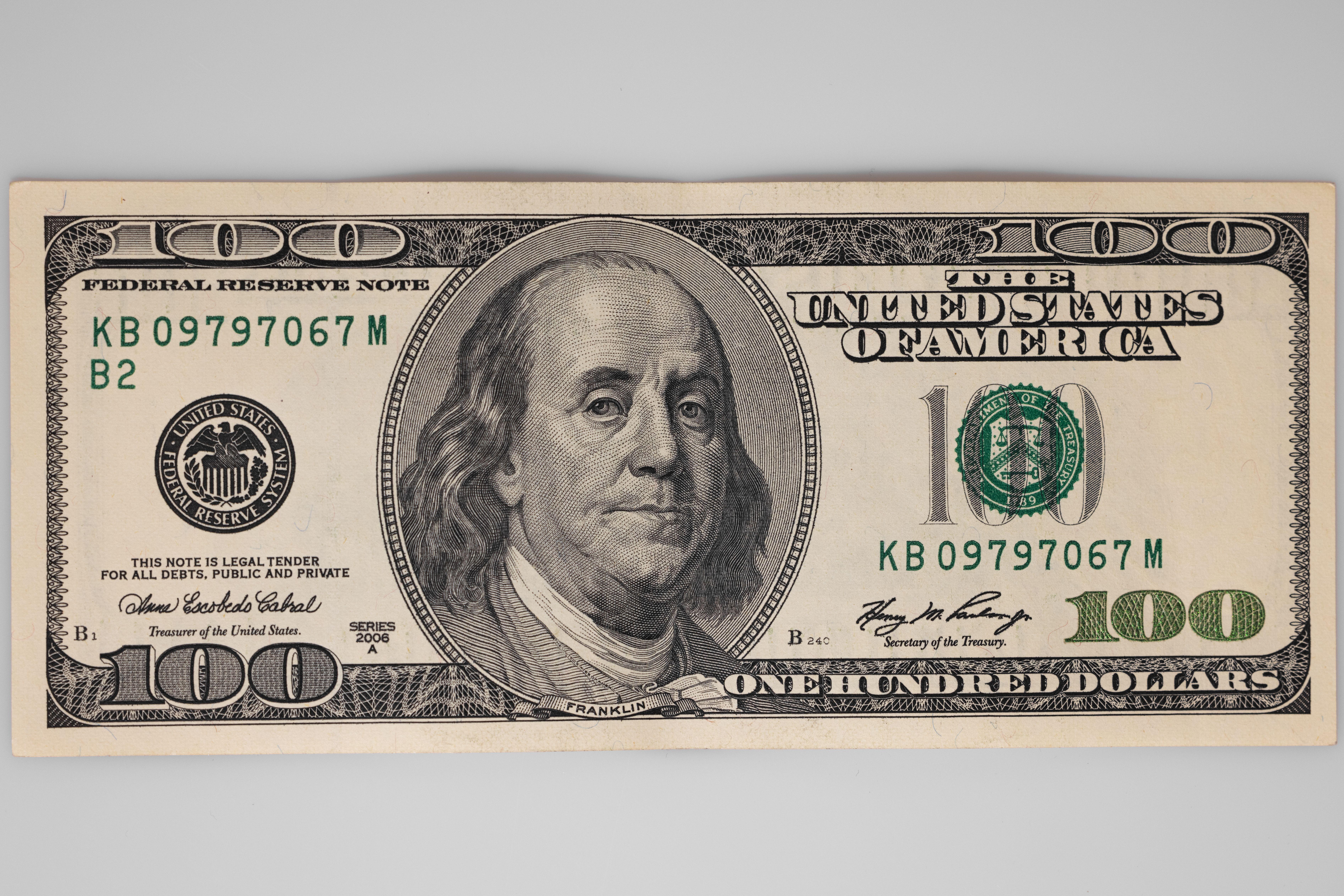 A detailed close-up of a US $100 bill featuring Benjamin Franklin on a white background.