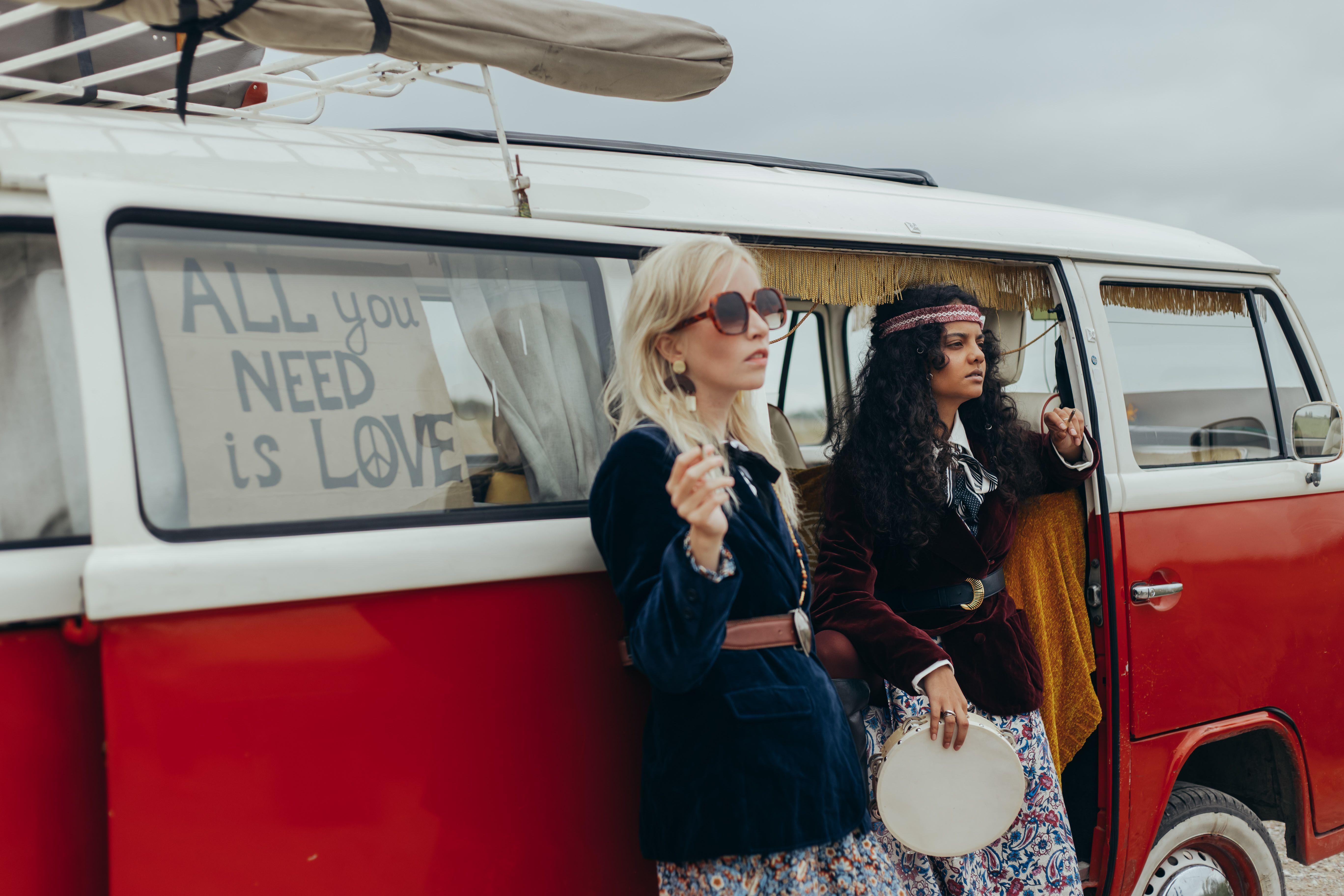 Two women in bohemian outfits by a vintage VW campervan on an adventurous road trip.