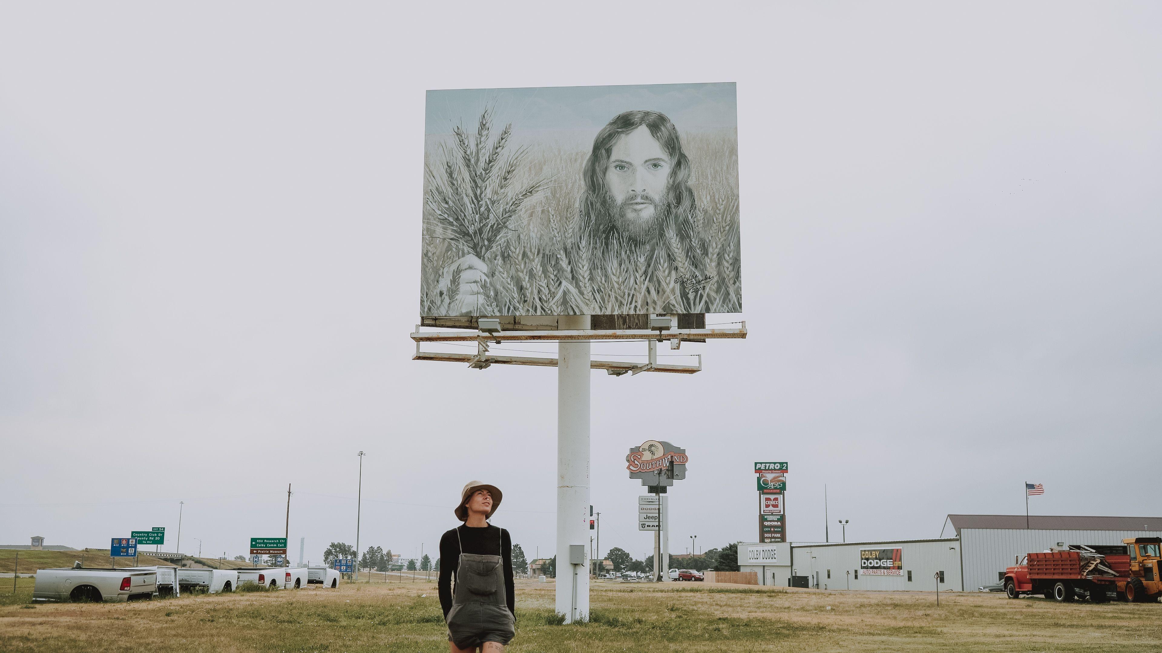 A person stands under the famous Wheat Jesus billboard along a highway in Colby, Kansas.
