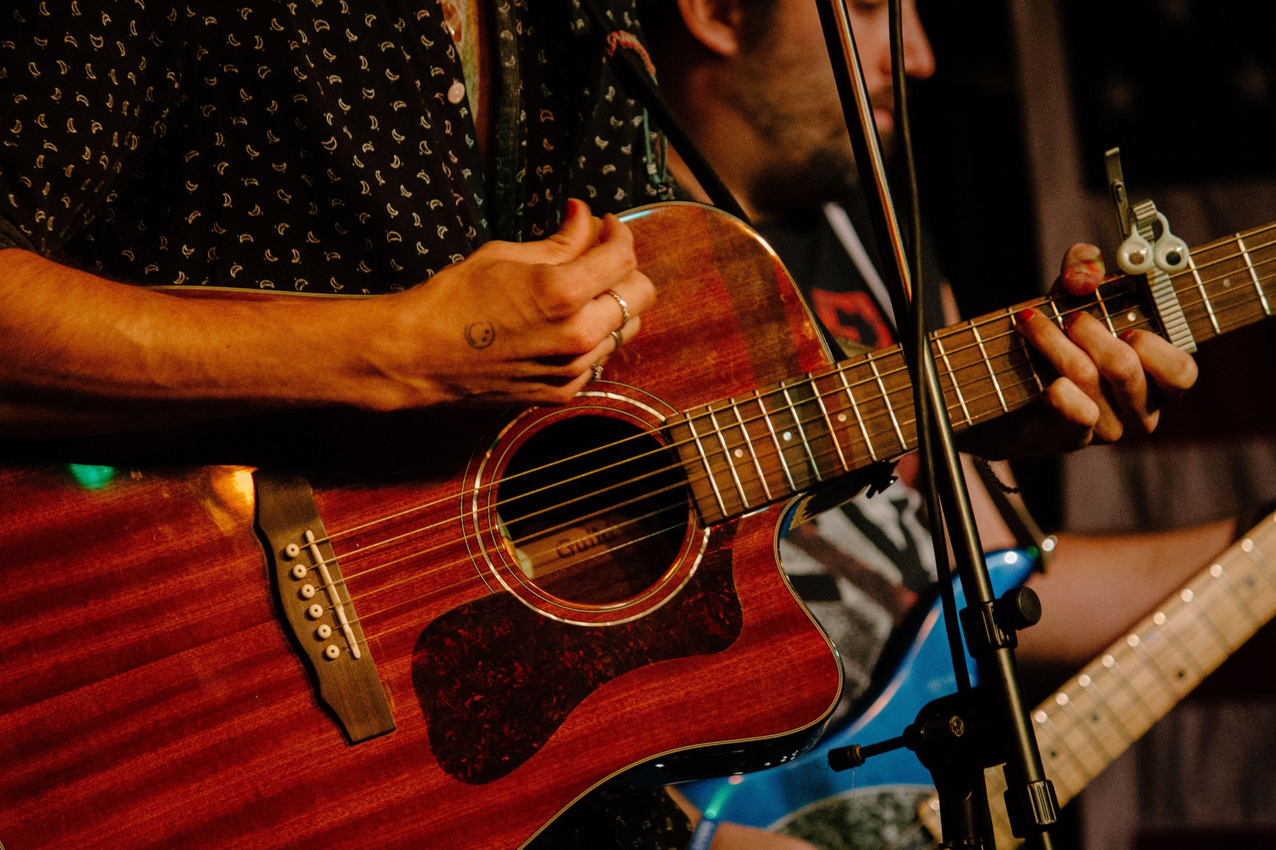 Hands playing an acoustic guitar during a live music performance in Boston.