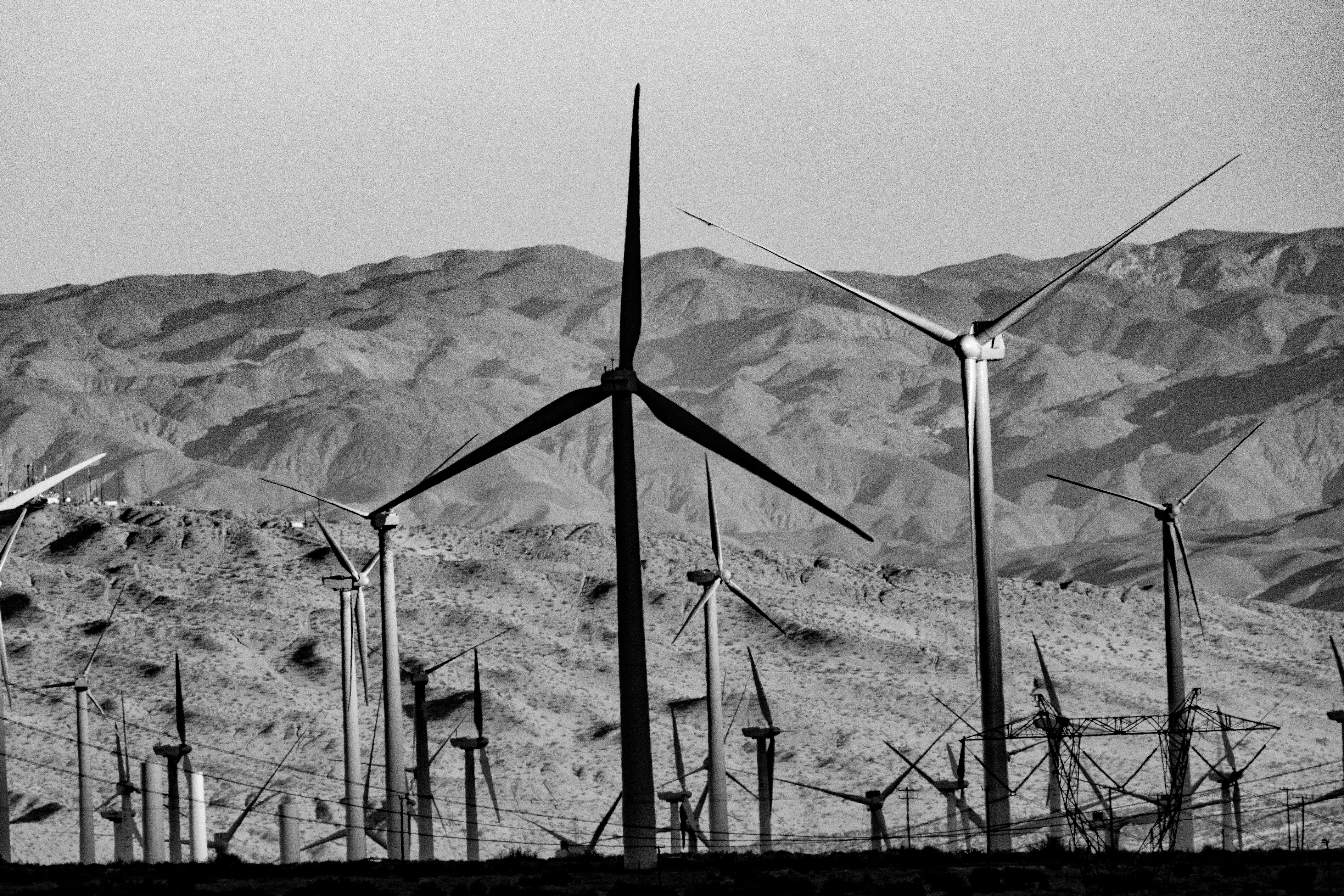 Black and white image of wind turbines against desert mountains in Cabazon, CA, highlighting renewable energy.