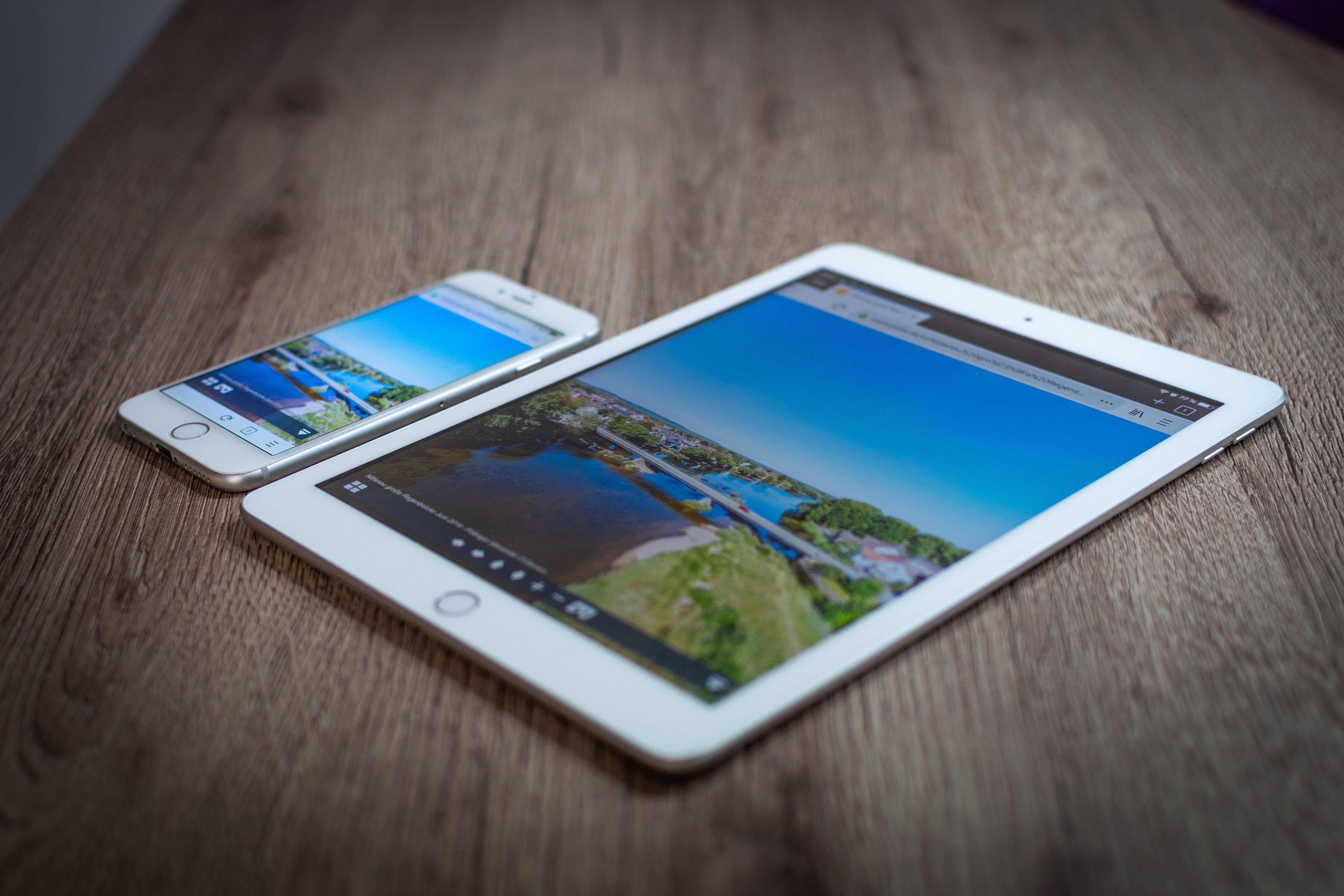 iPad and iPhone showing a scenic landscape on a wooden table, highlighting portability and technology.