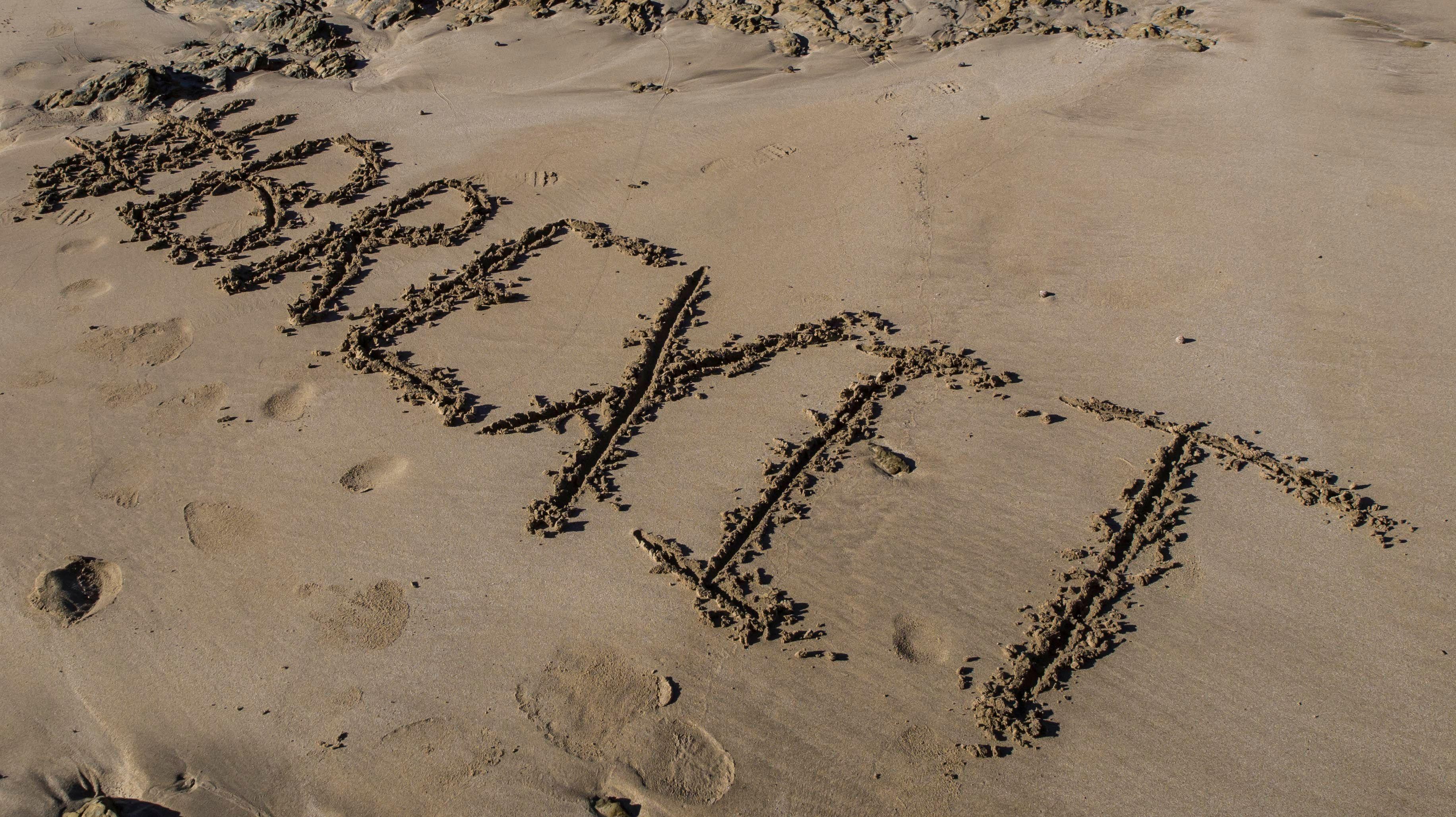 'Brexit' inscribed on sandy beach with footprints around it.