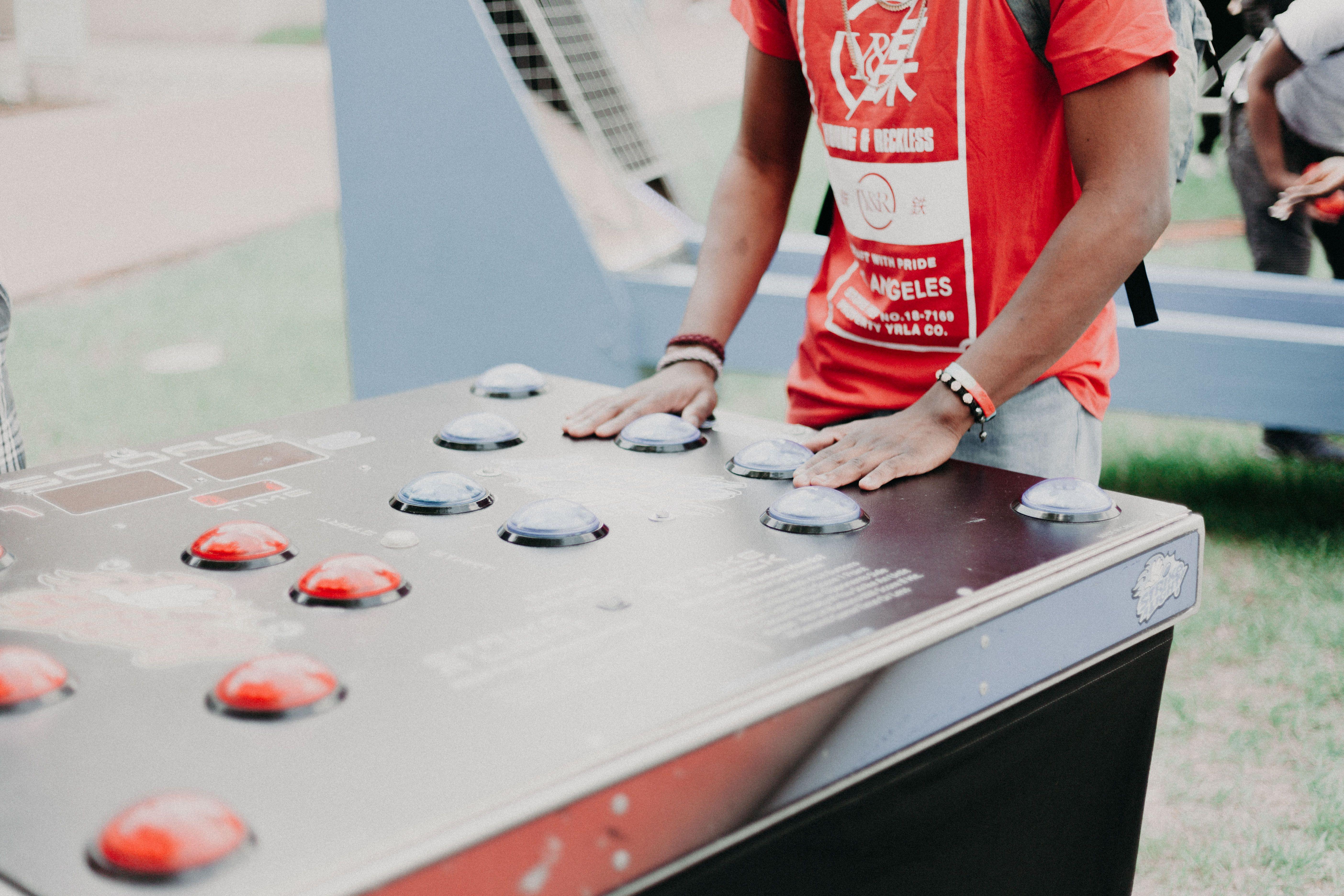 Group of young adults enjoying outdoor arcade buttons game in a park setting.