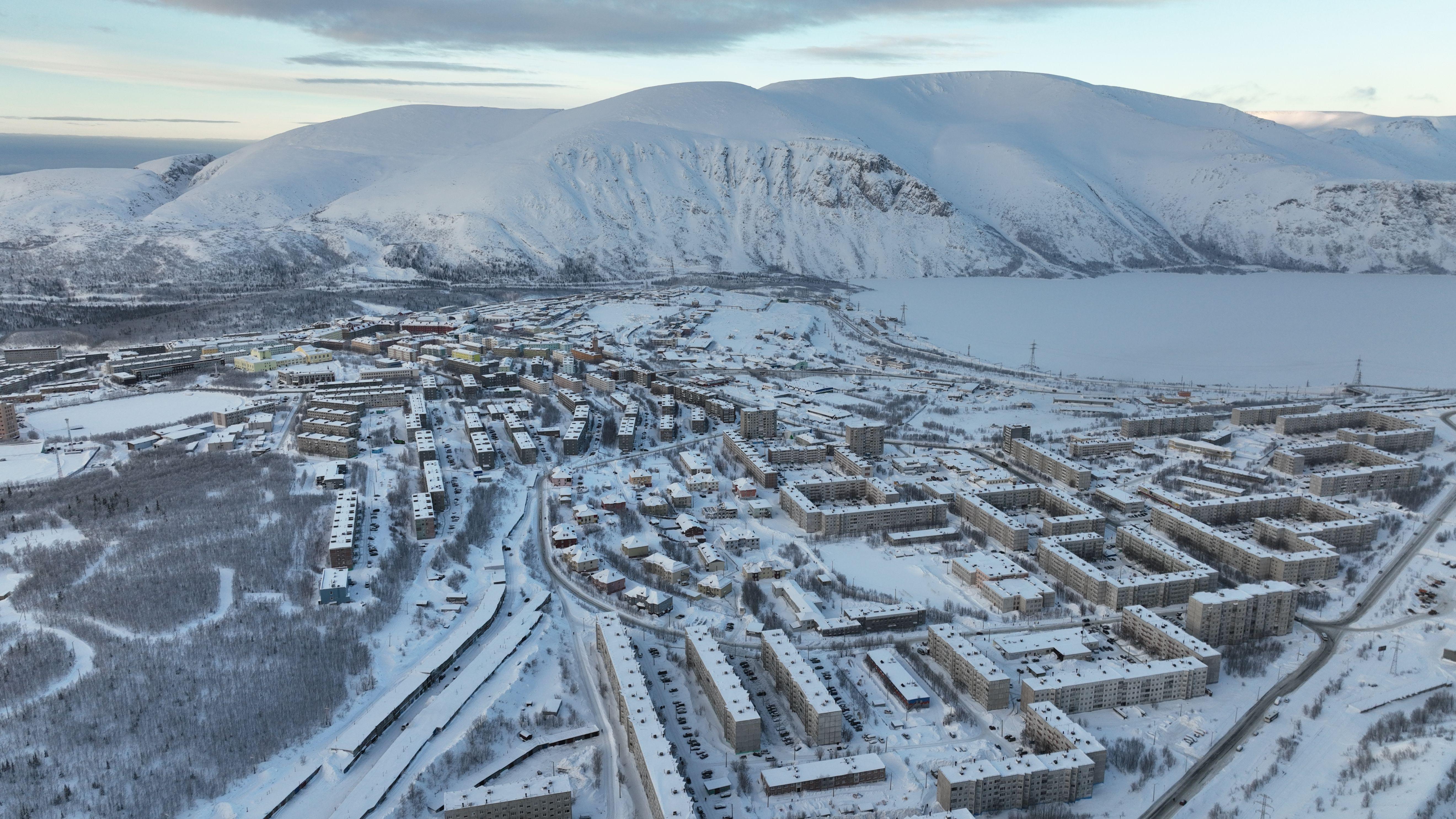 Aerial view of Kirovsk, Russia, showcasing snow-covered town and mountains in winter.