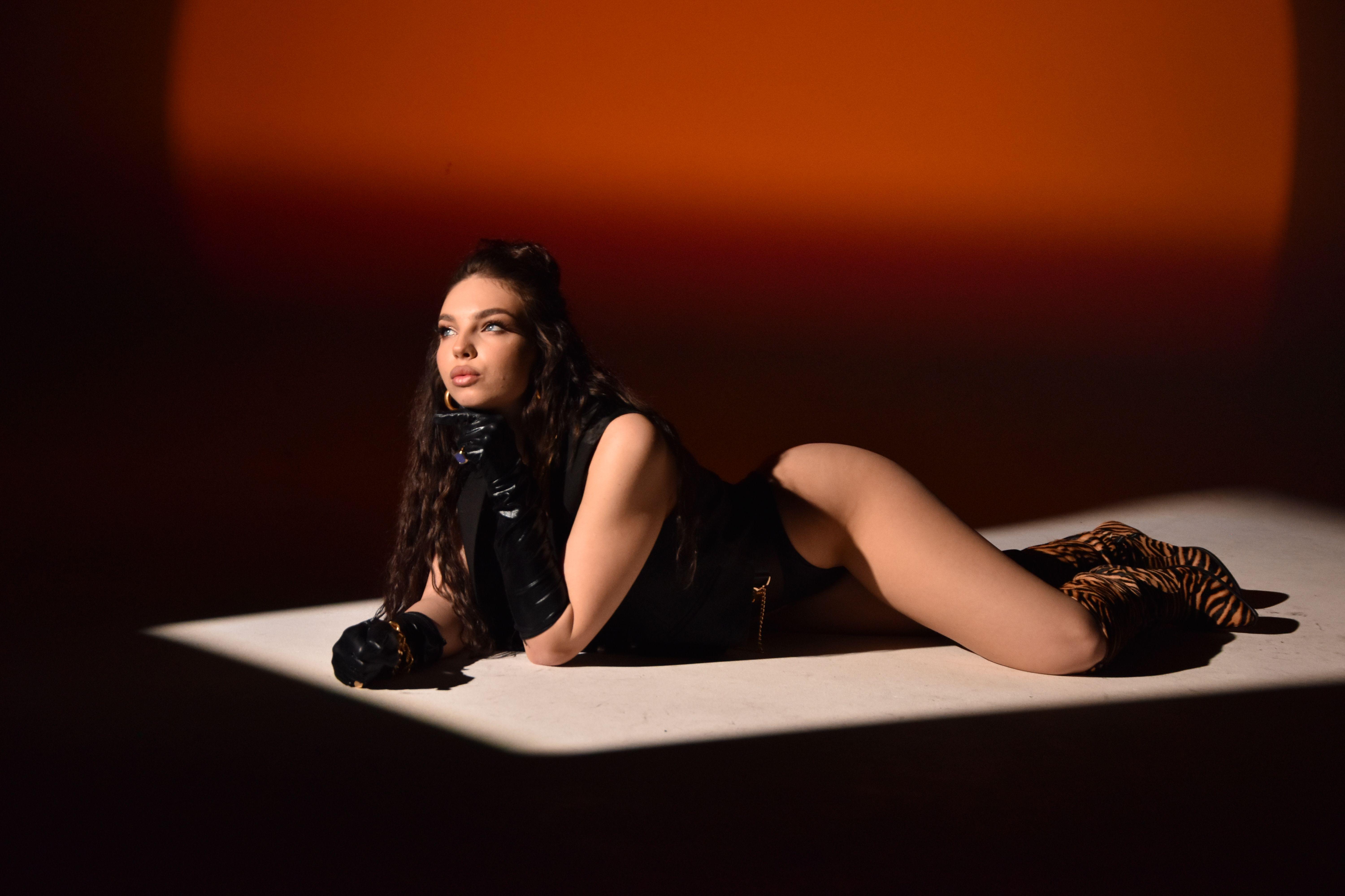 Stylish indoor portrait of a woman posing in elegant attire with dramatic lighting.