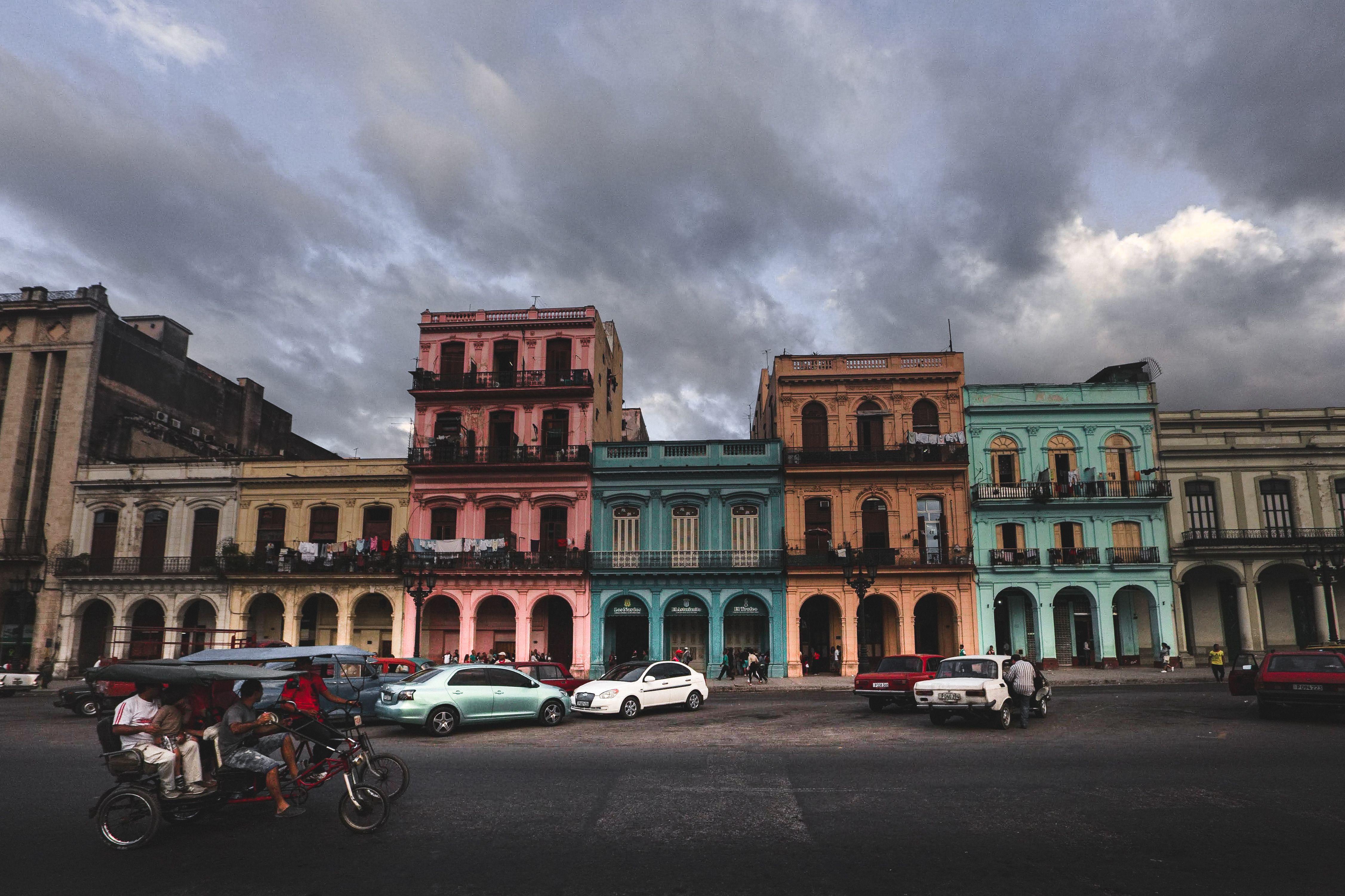Vibrant colonial buildings in Havana under a moody sky with street activity.