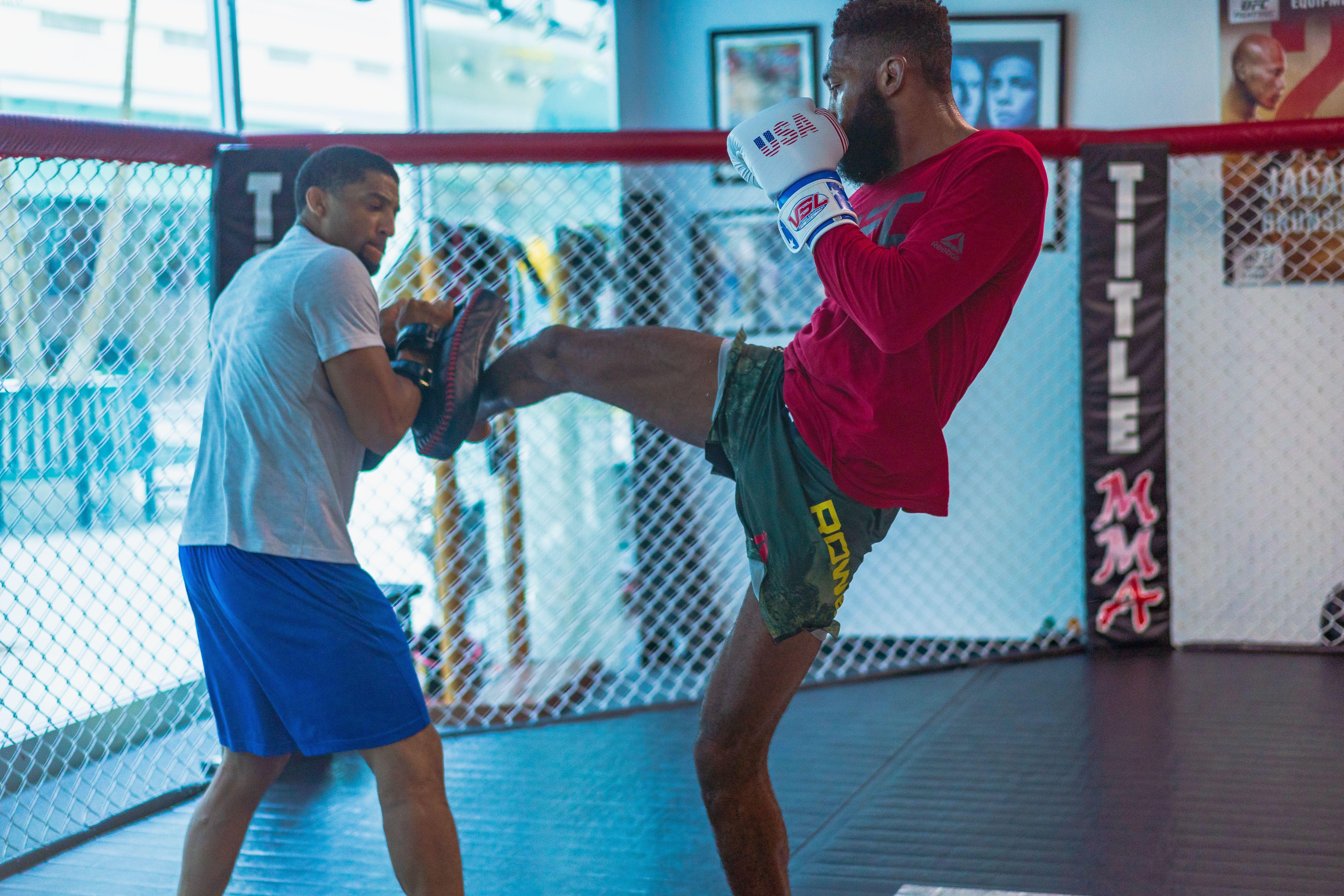Dynamic kickboxing training session featuring two athletes in action inside a gym.
