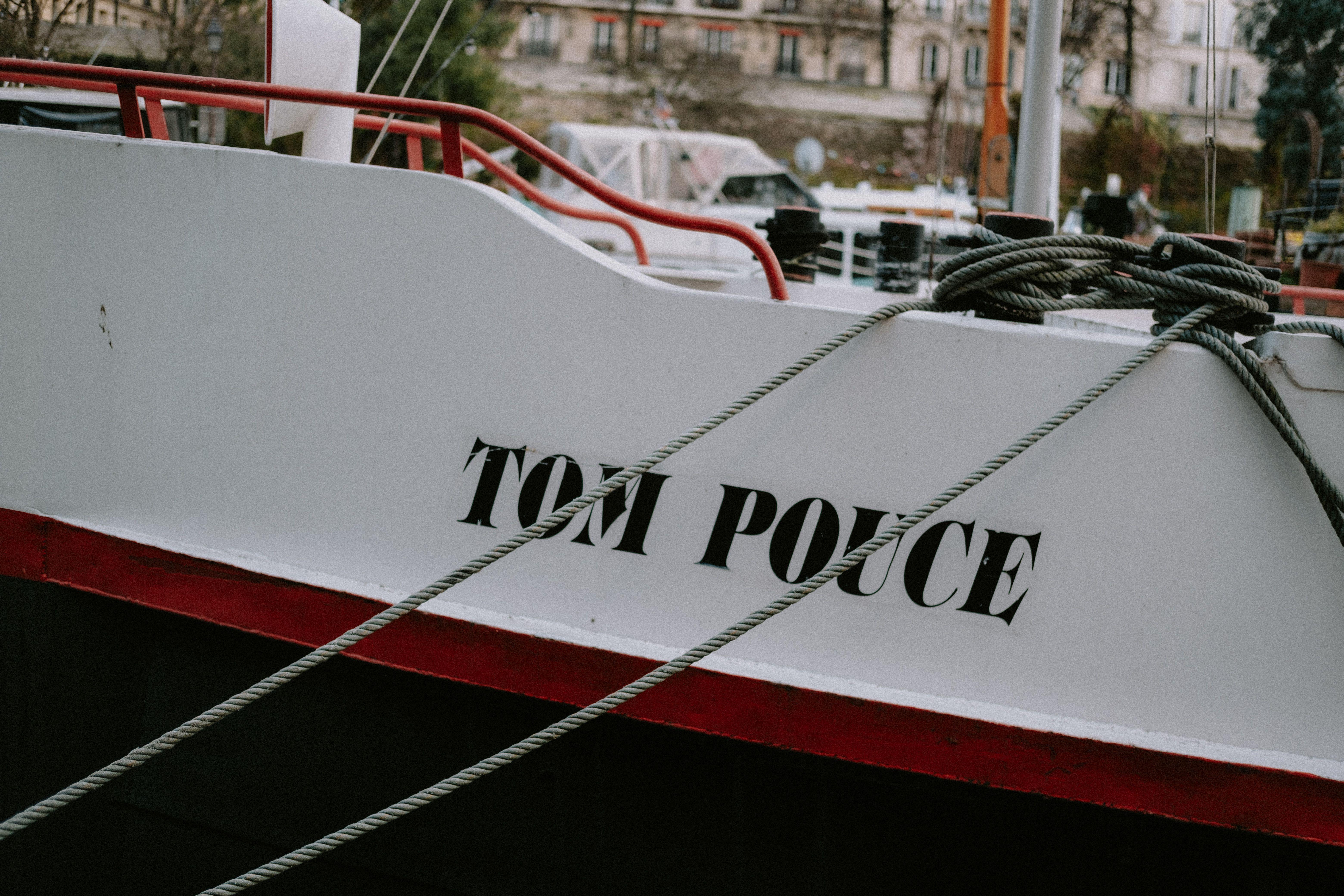A close-up of a moored boat named 'Tom Pouce' with detailed ropes and dockside elements.