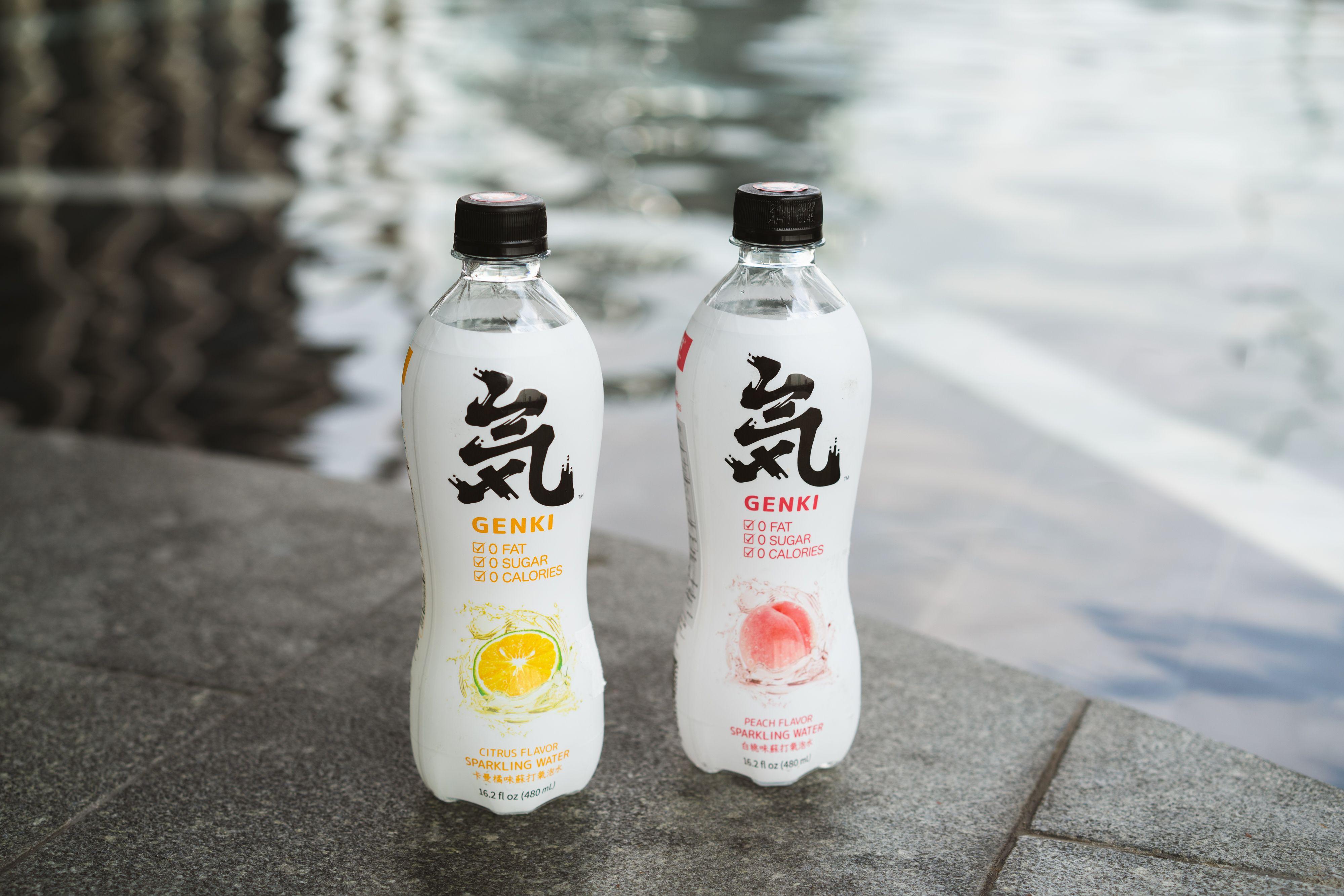 Close-up shot of Genki sparkling water bottles by the poolside, showcasing citrus and peach flavors.