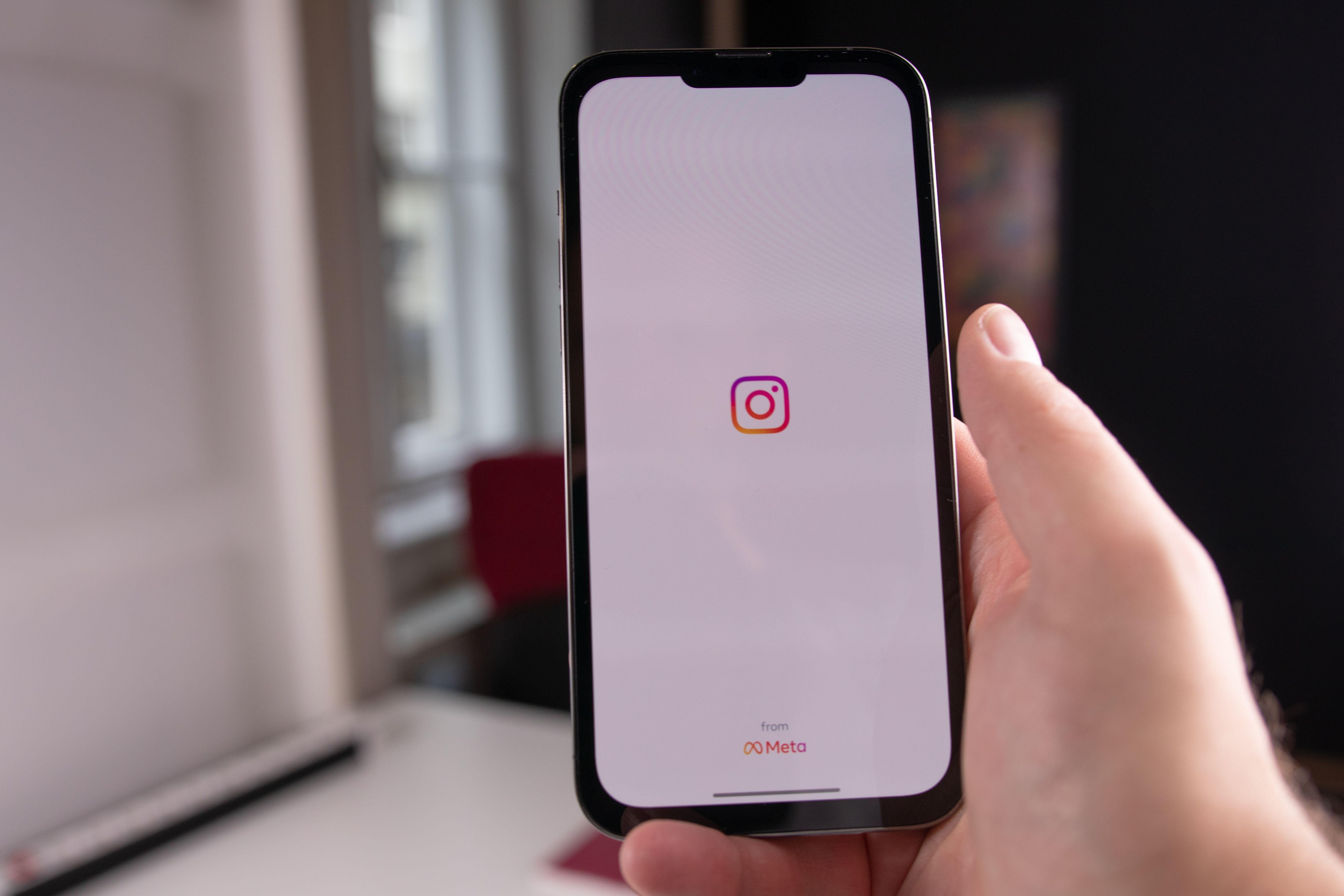 Close-up of a hand holding a smartphone displaying the Instagram app, indoors in Budapest.
