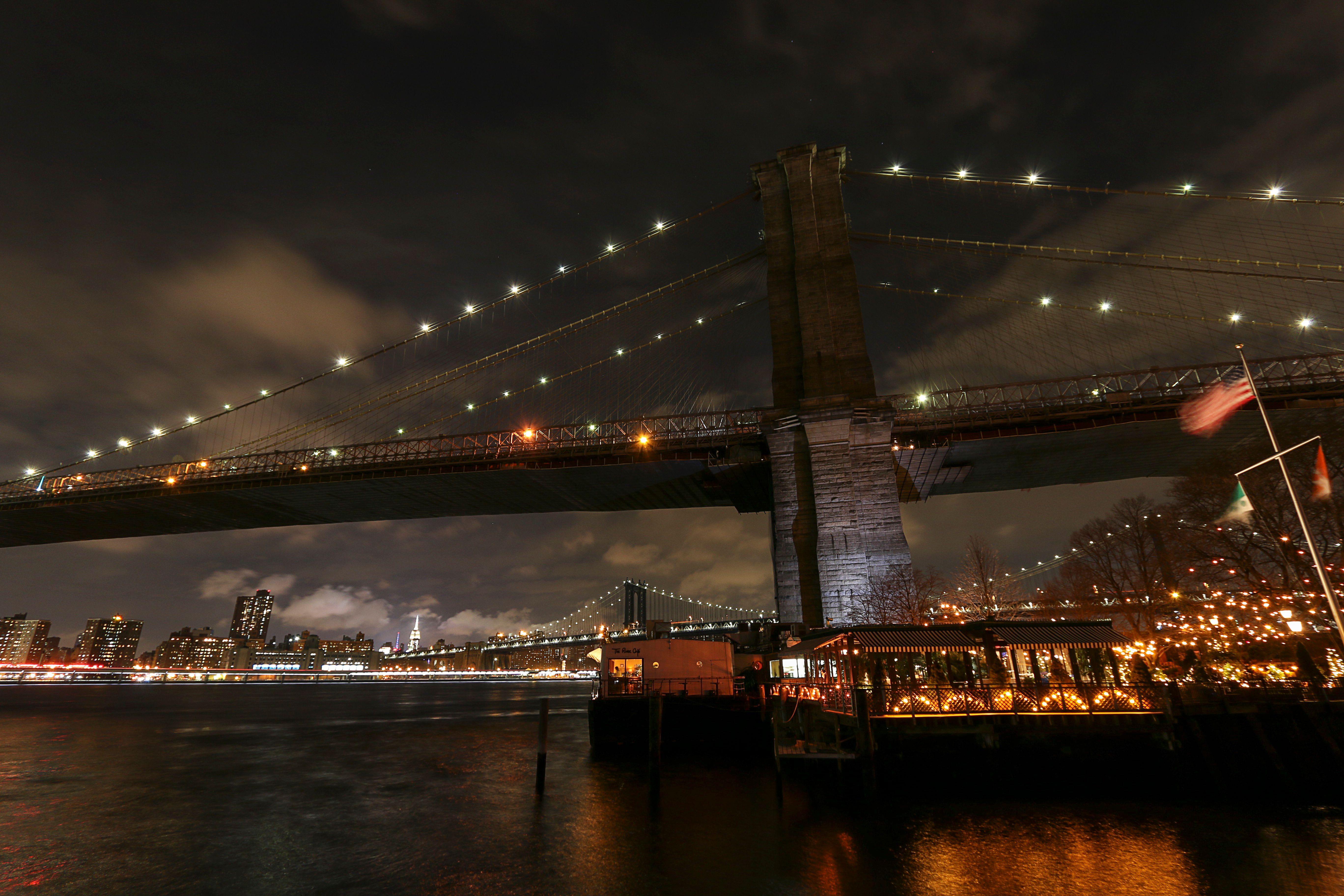 Captivating view of Brooklyn Bridge at night with New York City skyline in the background.