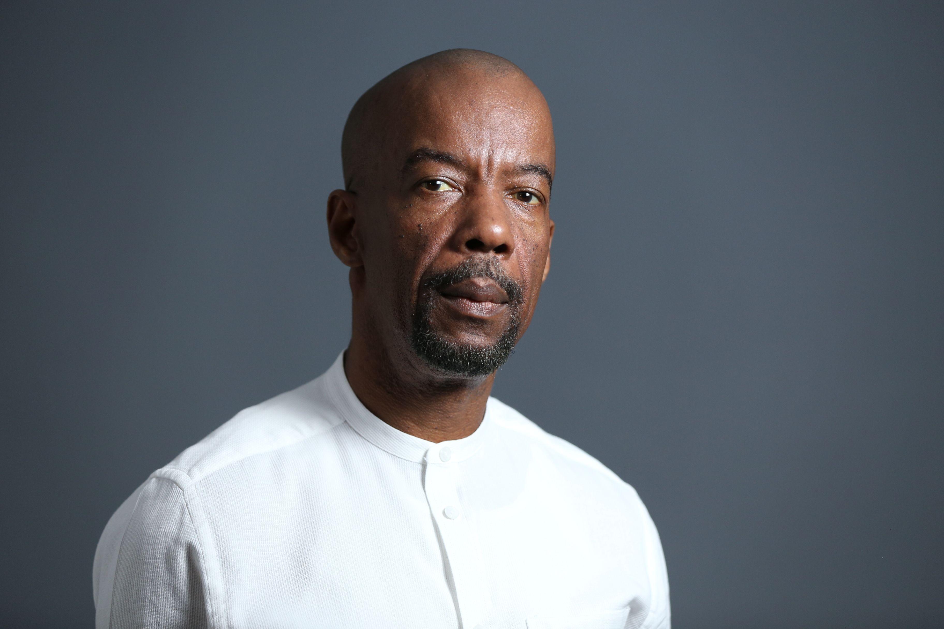 Portrait of a middle-aged African American man in a white shirt with a neutral background.