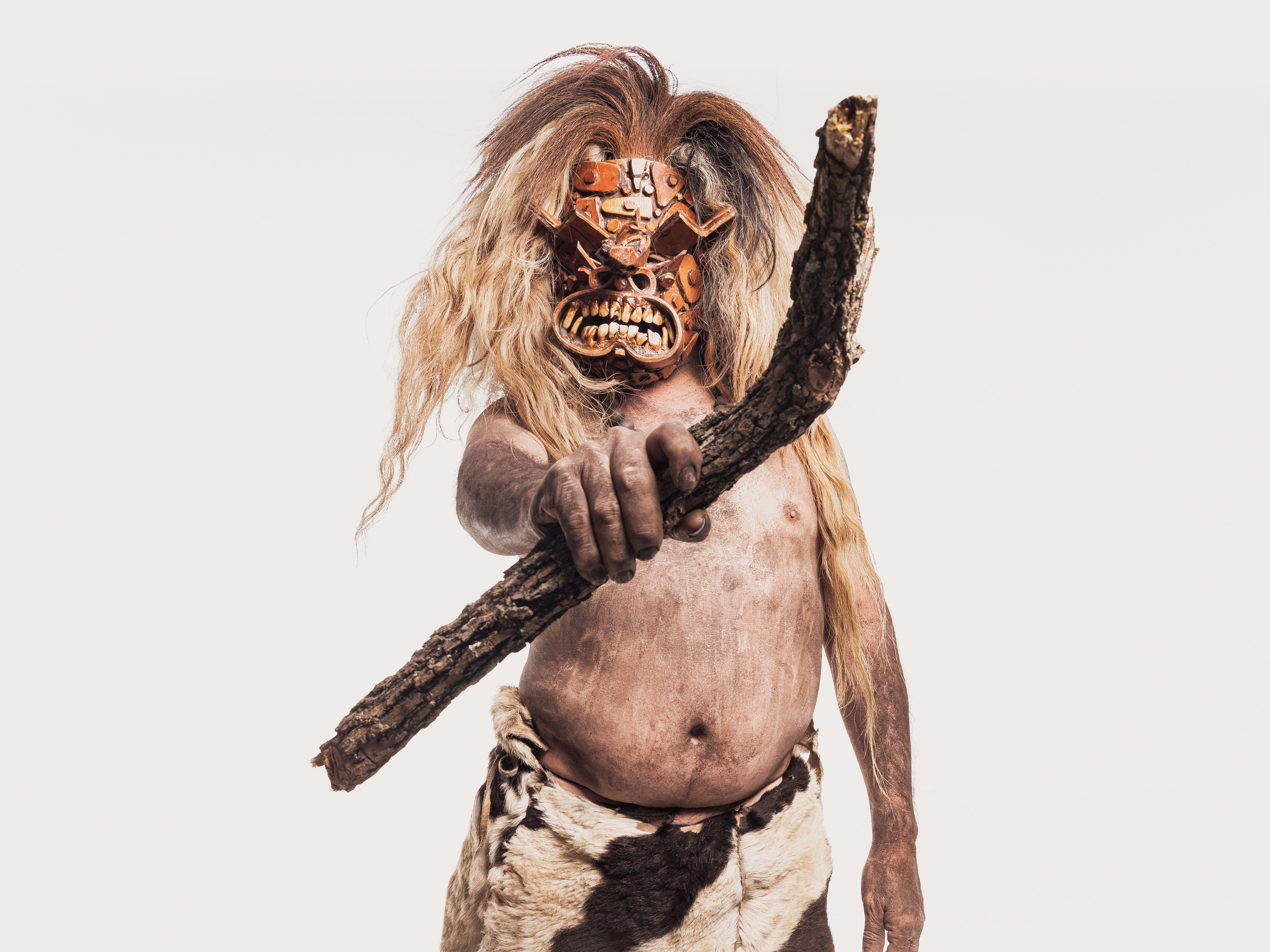A man in traditional Mexican costume and mask holding a stick, embodying cultural heritage.