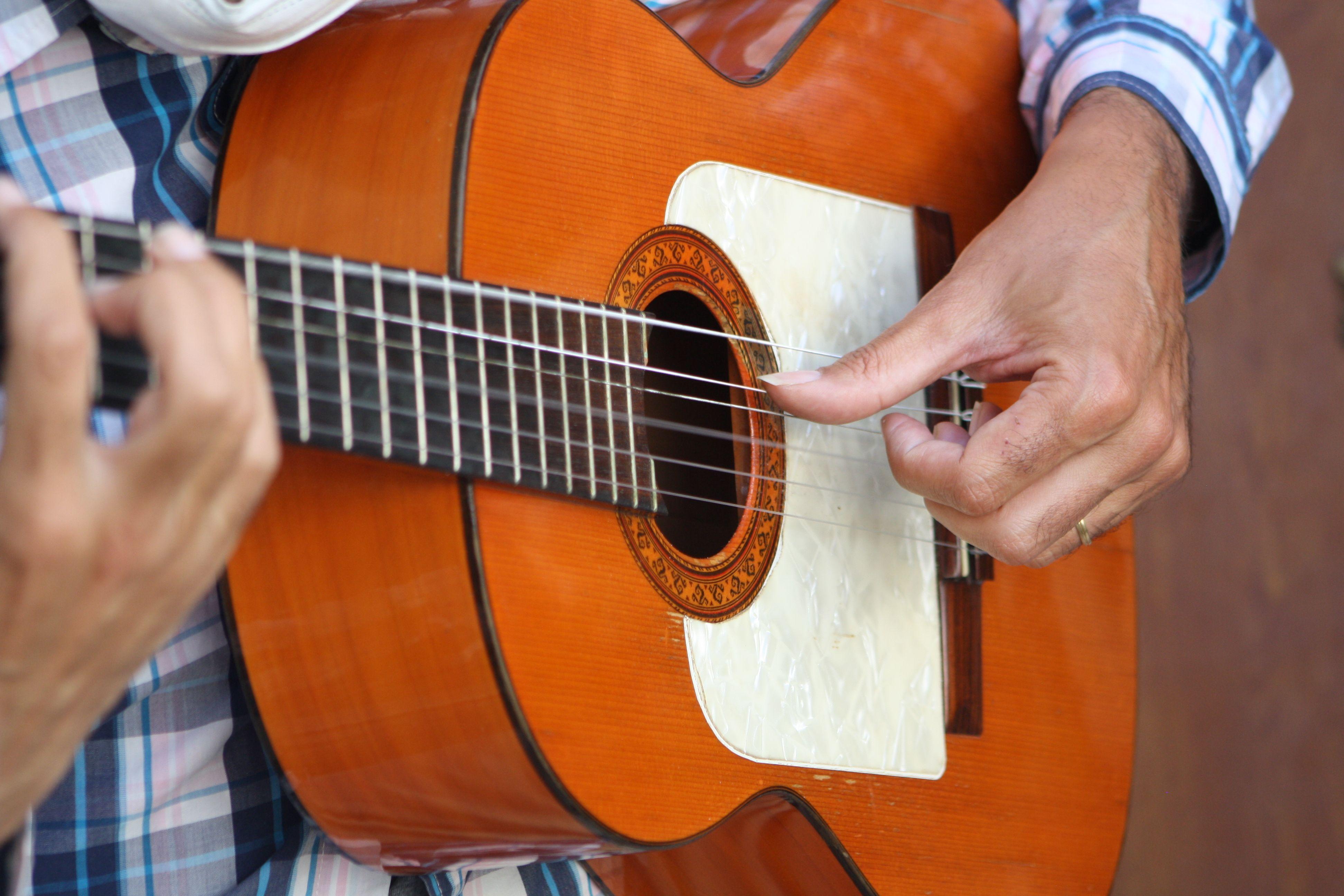 A detailed close-up of a flamenco guitarist's hands strumming a wooden guitar in Córdoba, Spain.