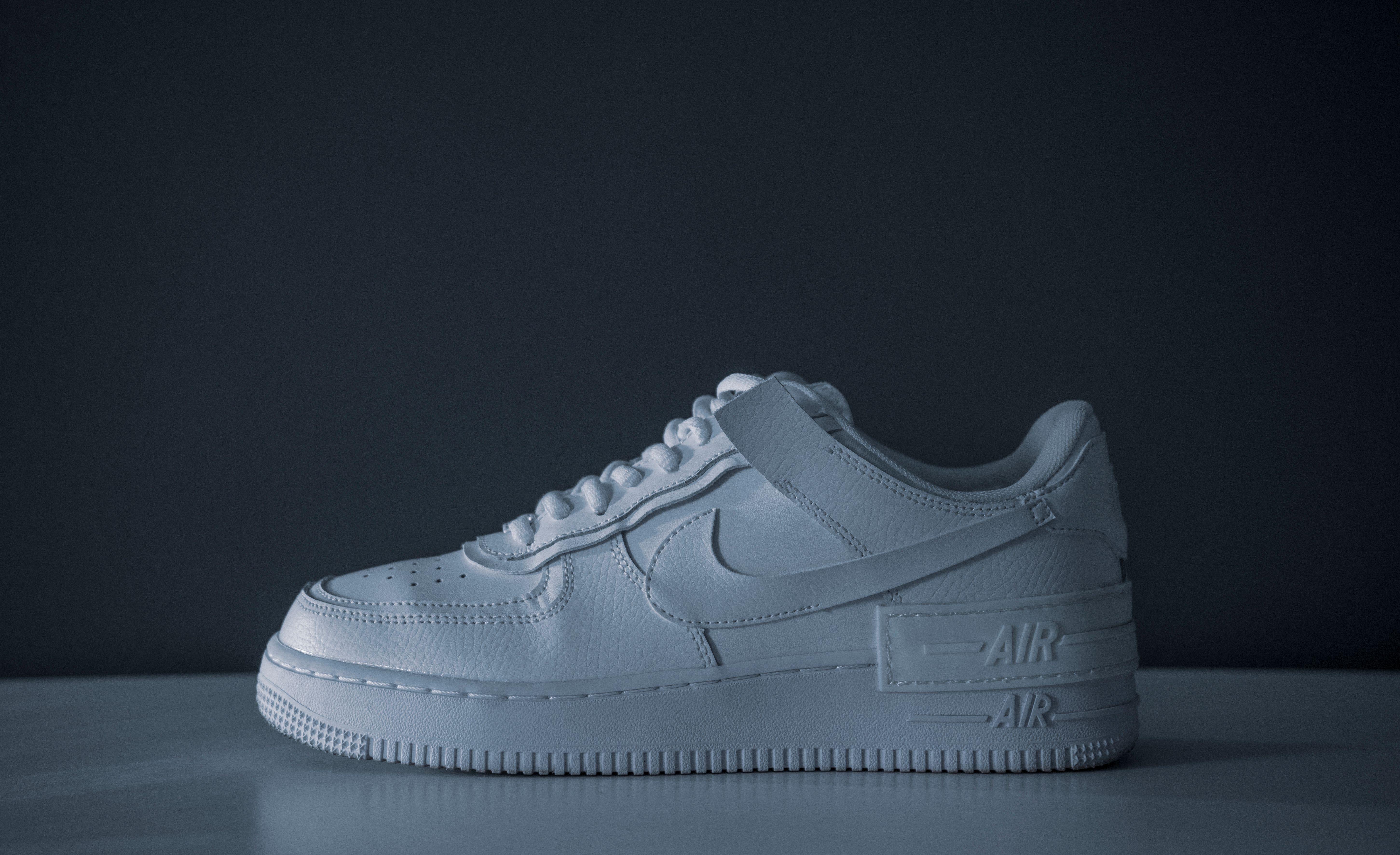 Minimalist image of a white sneaker on a dark background showcasing modern style.
