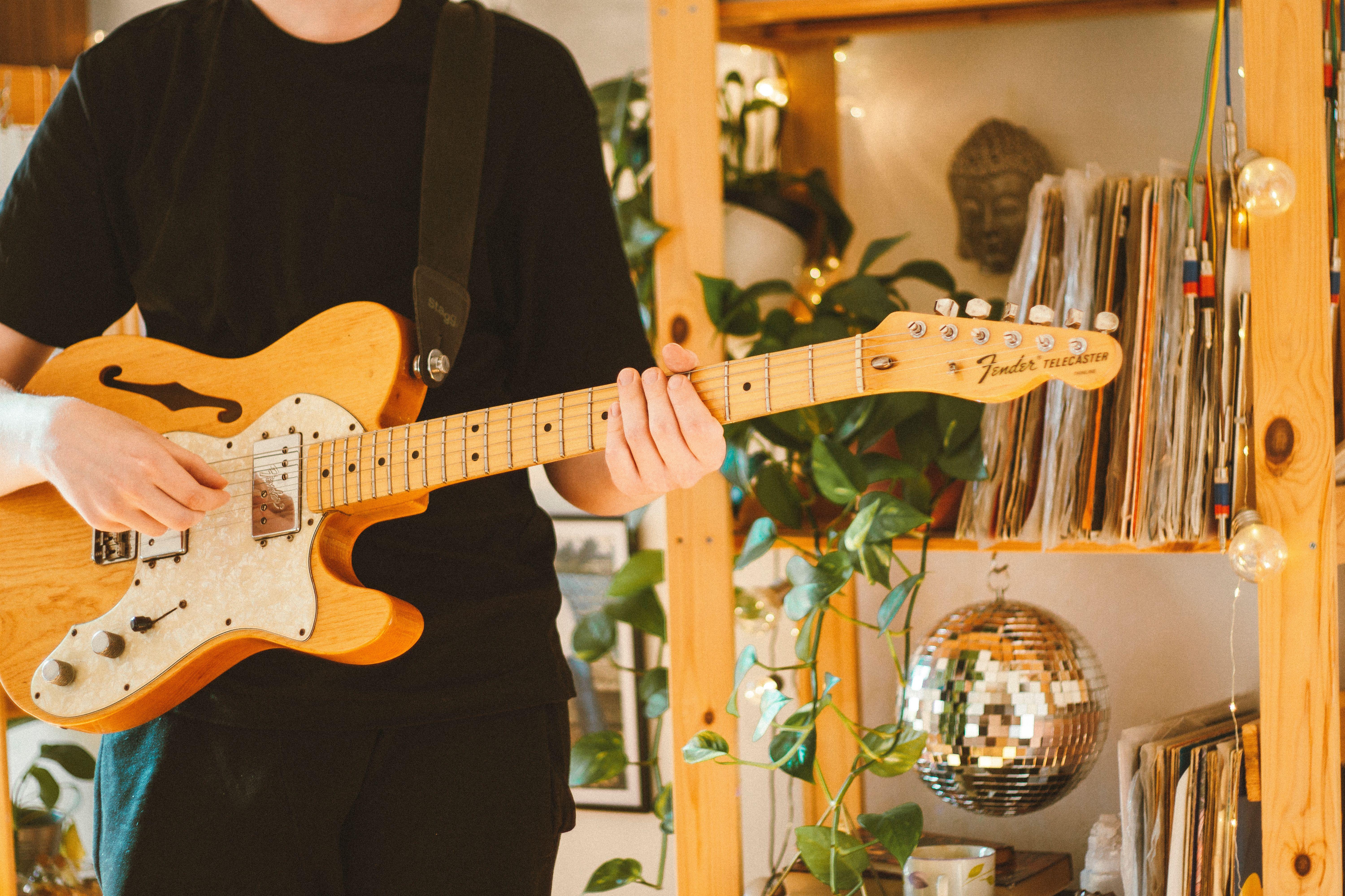 Close-up of a musician playing a Fender electric guitar indoors.