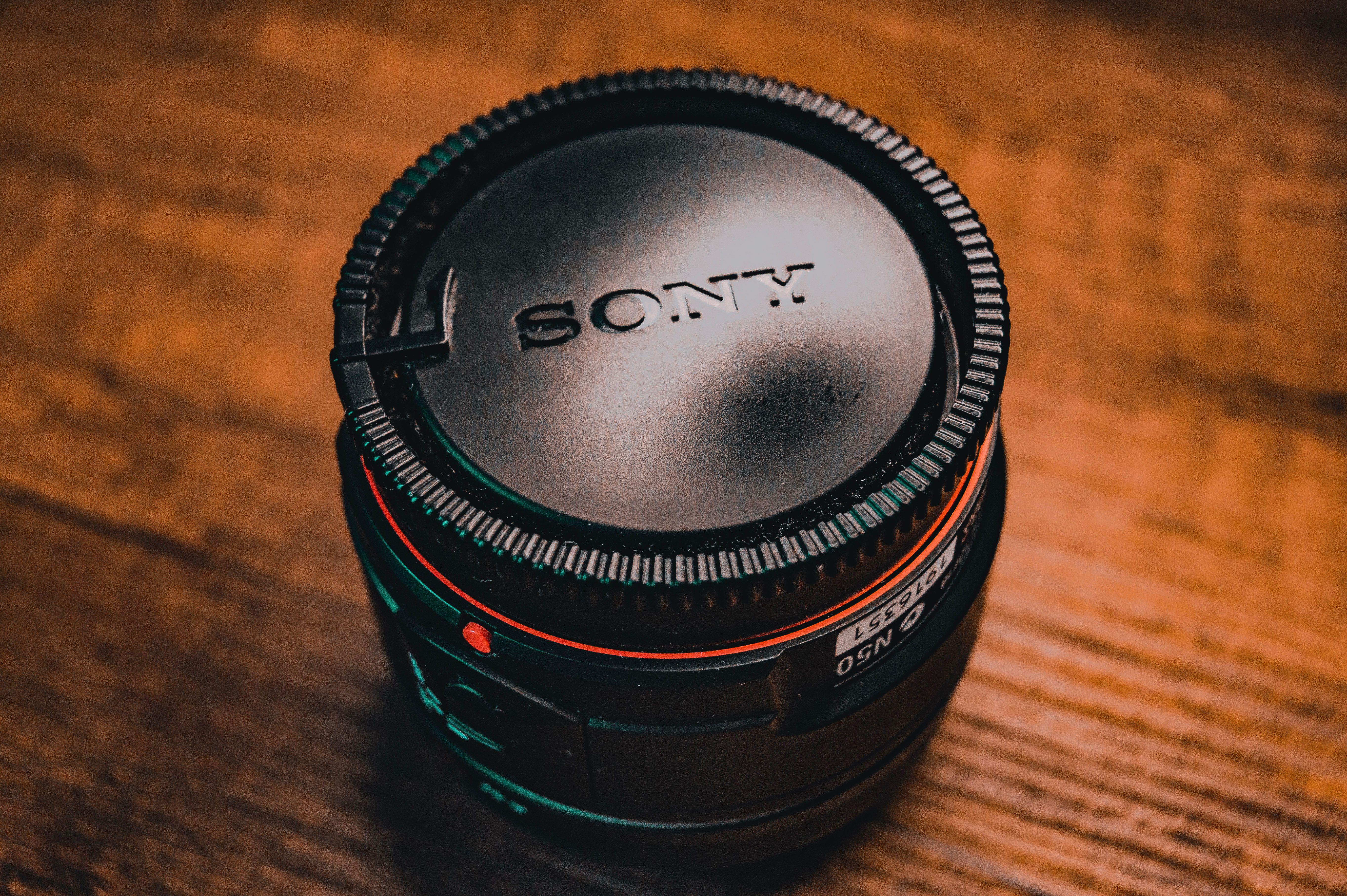 Detailed view of a camera lens on a textured wooden surface, showcasing fine details.