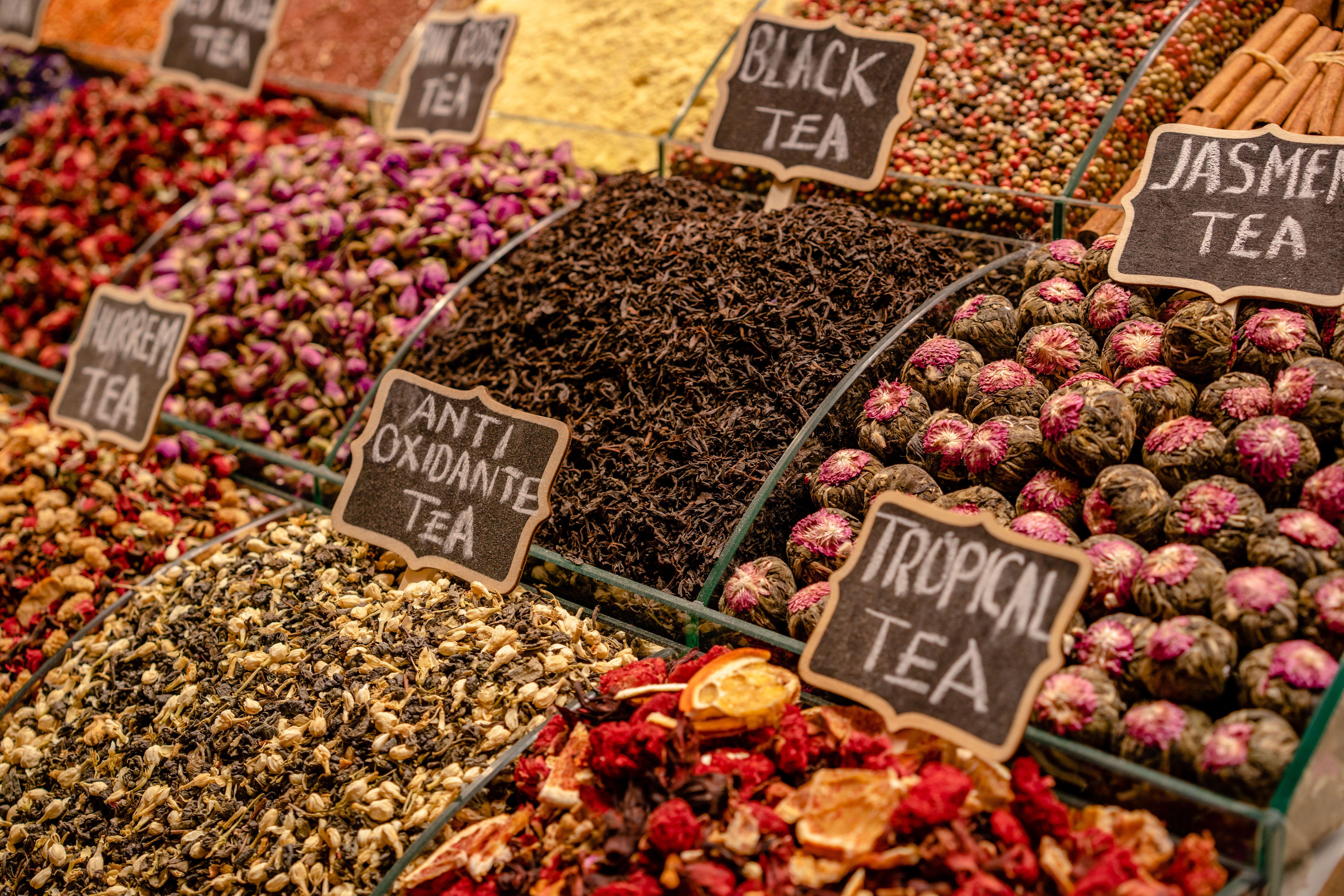A vibrant display of various teas at a market stall, highlighting diverse flavors and colors.