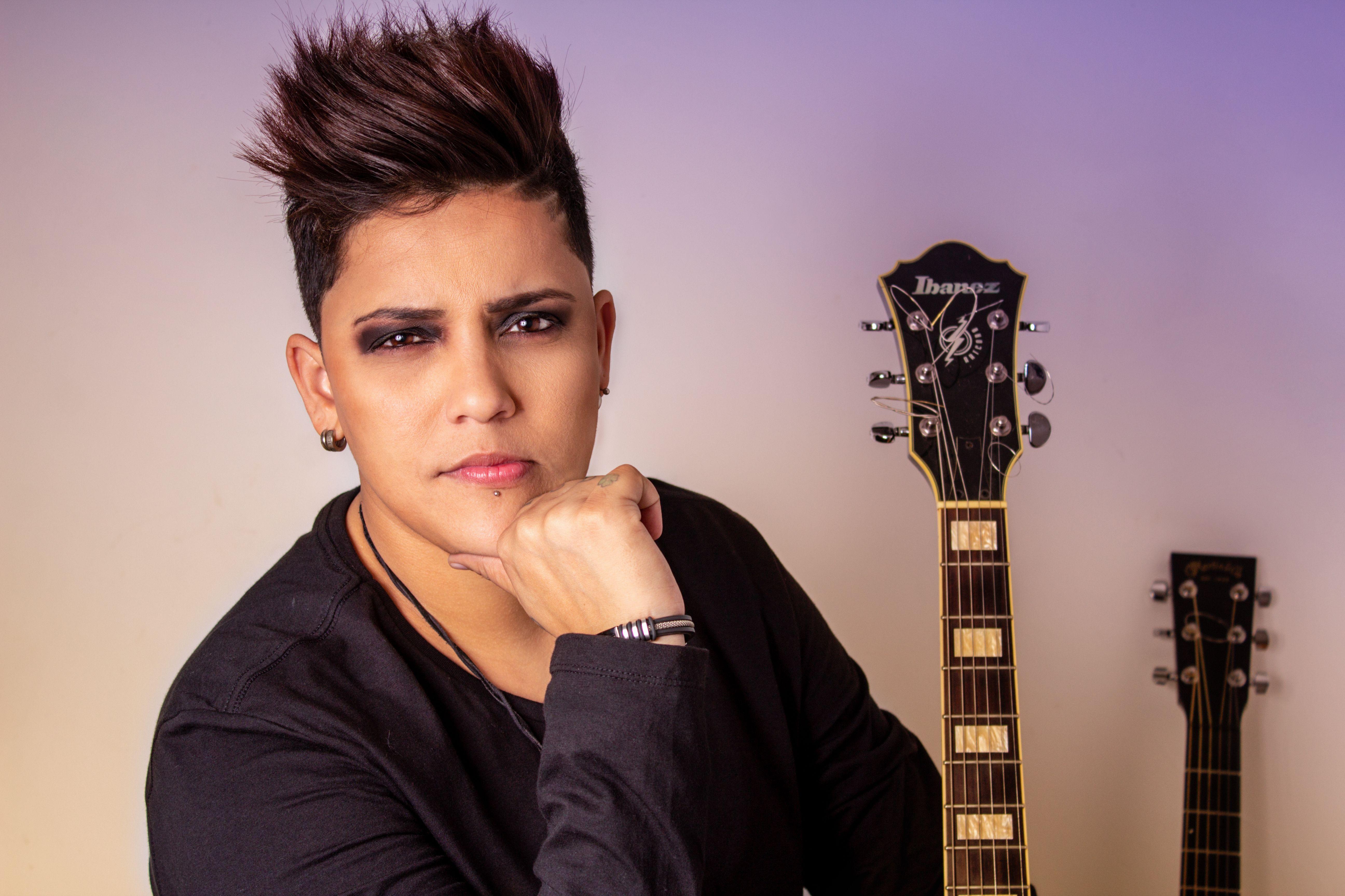 Stylish musician posing with electric guitar in a studio setting, exuding confidence and rock attitude.
