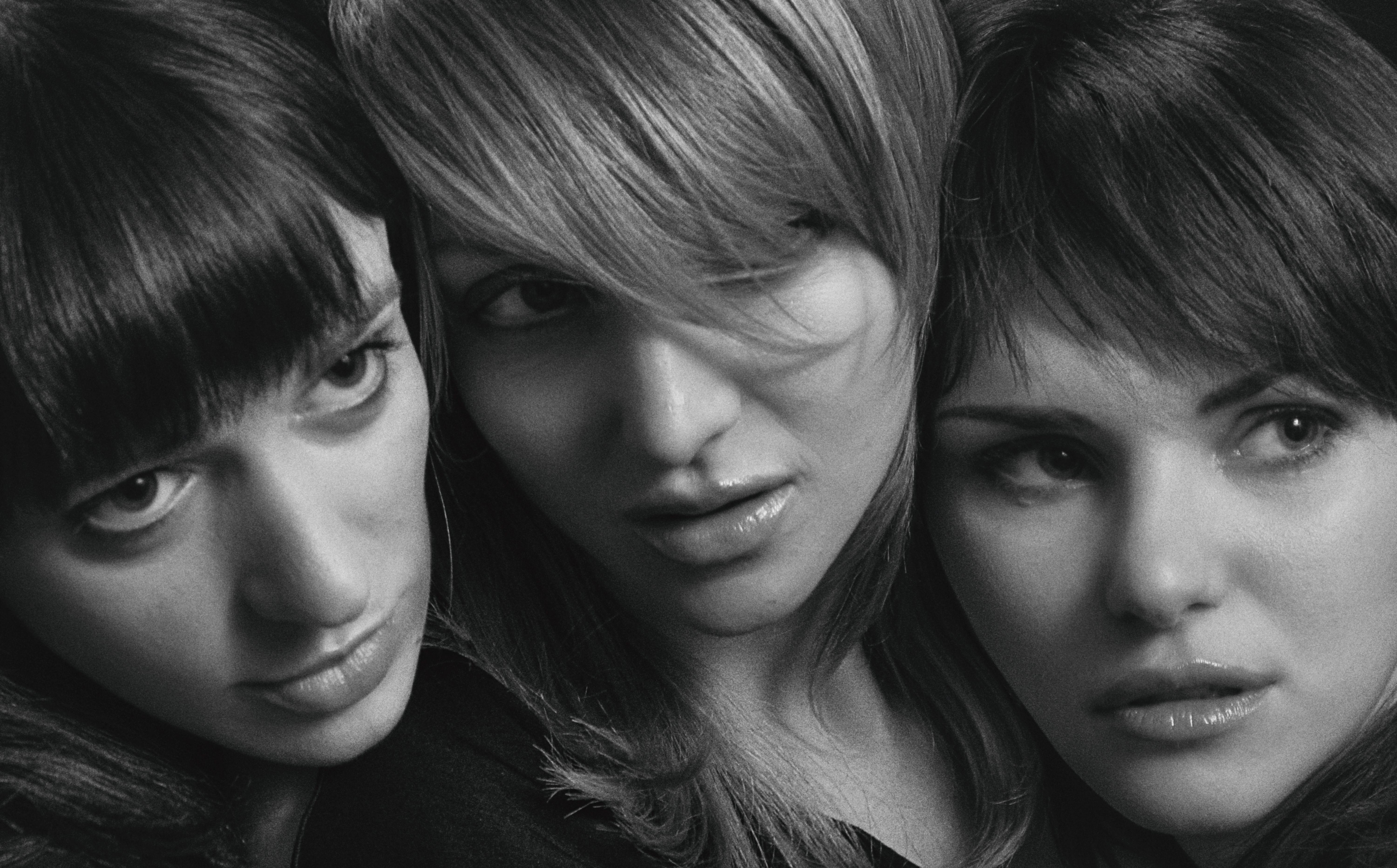 Black and white close-up portrait of three women showcasing different hairstyles, expressing various emotions.