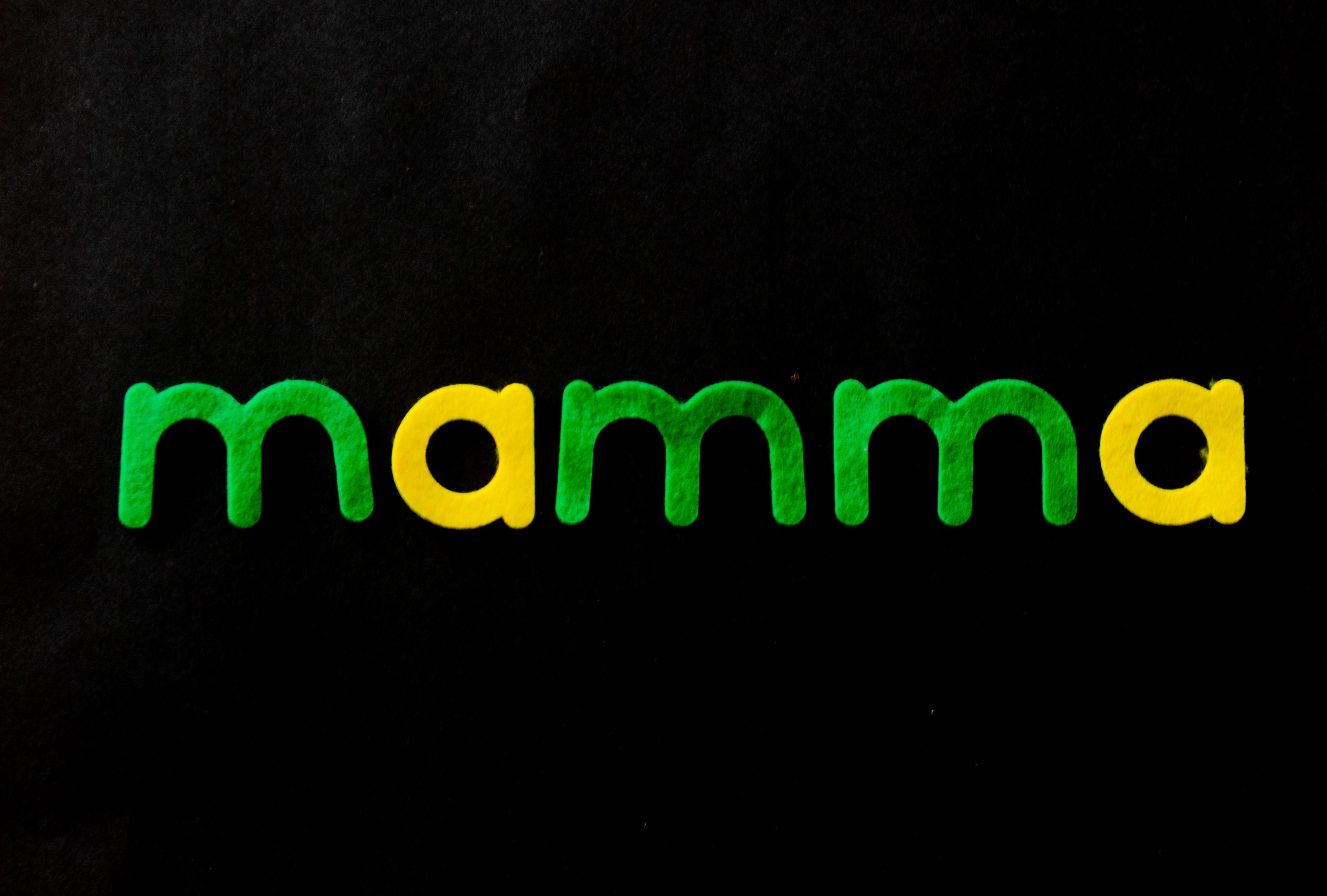 Close-up of the word 'mamma' in vibrant colors on a dark background.