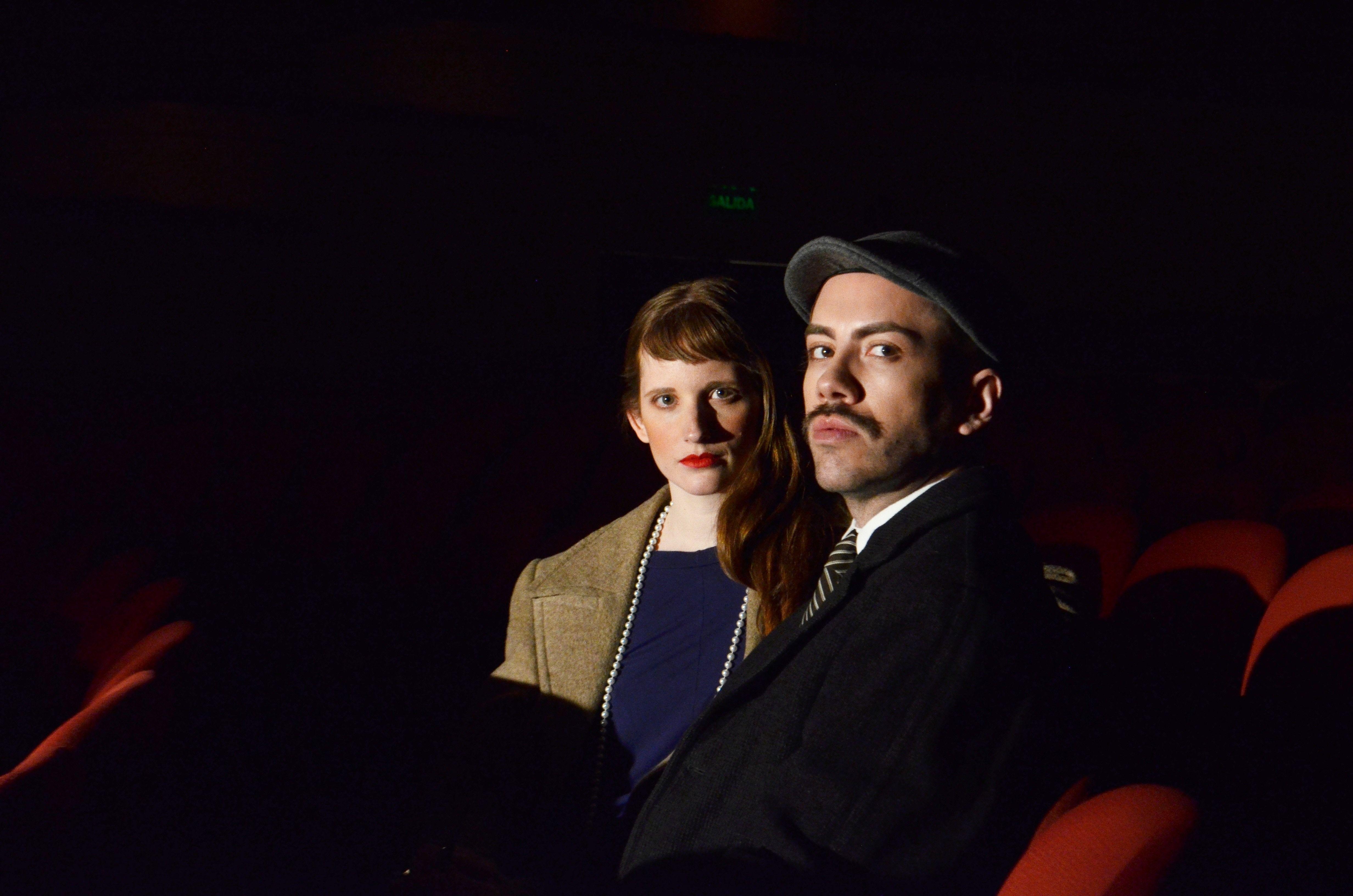 A man and woman sitting in a dimly lit theater, adding a vintage touch.
