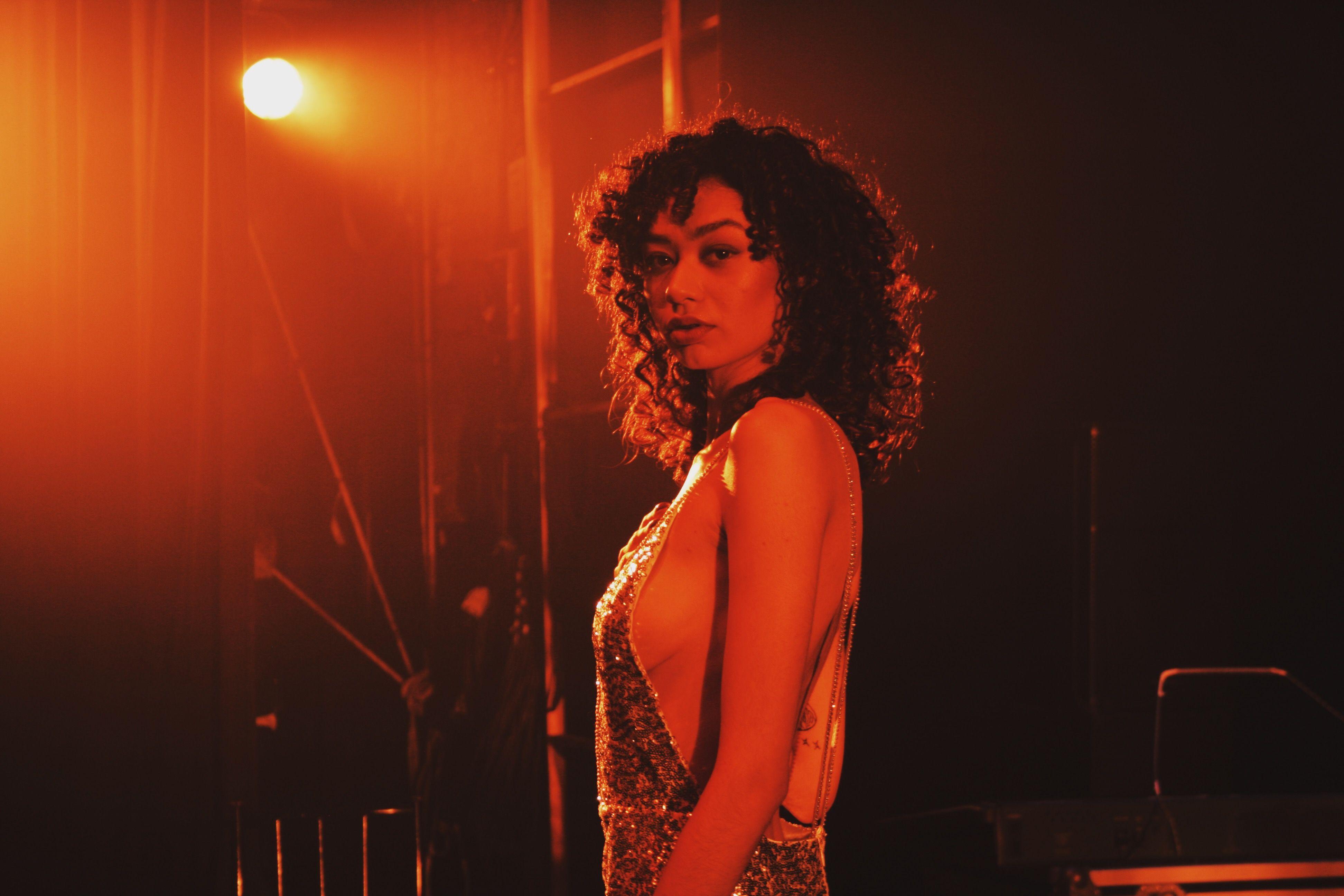 A woman in a glamorous dress poses under dramatic spotlight, captured with a Canon EOS 400D.