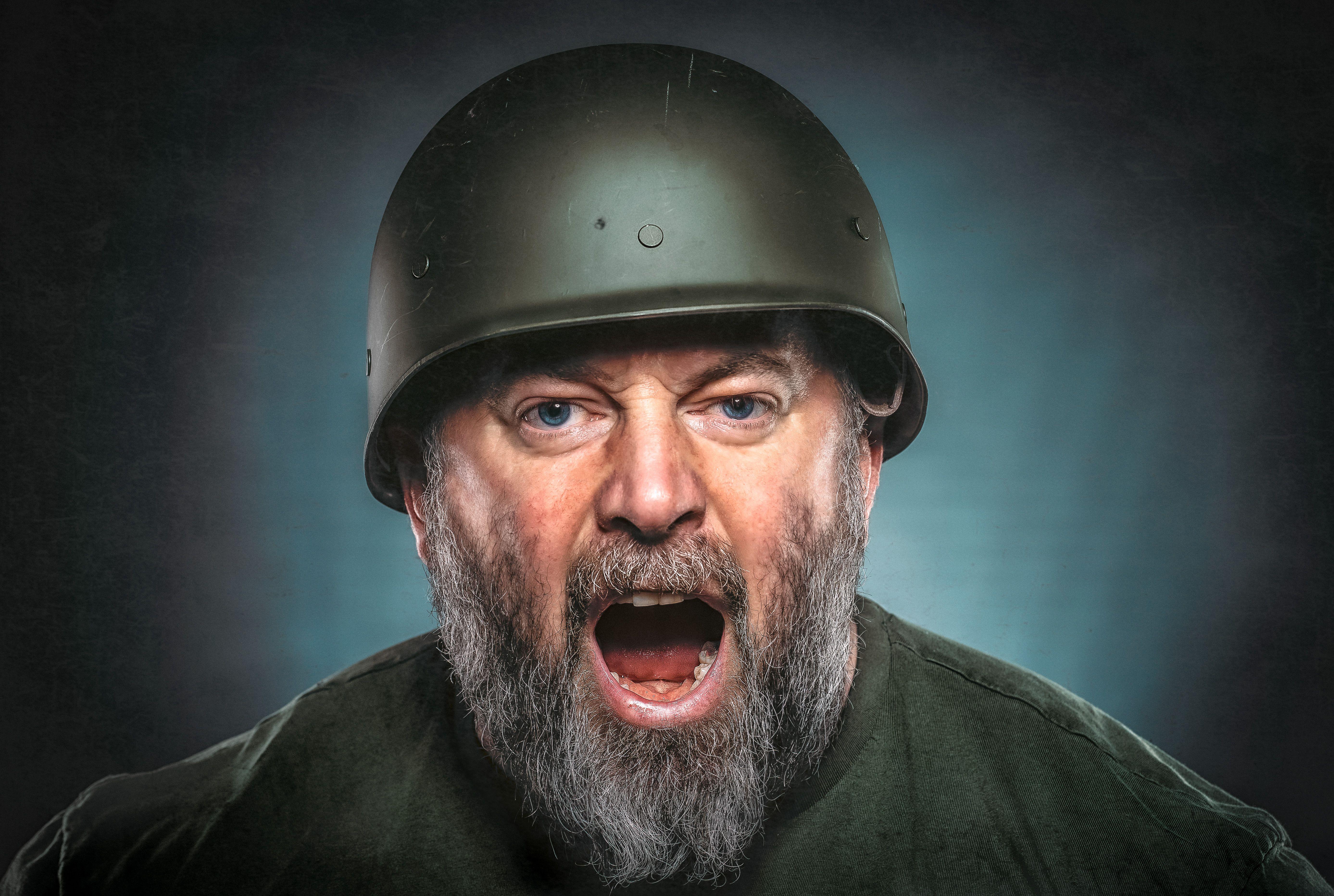 Intense portrait of a bearded man in a helmet shouting. Dramatic expression captured.