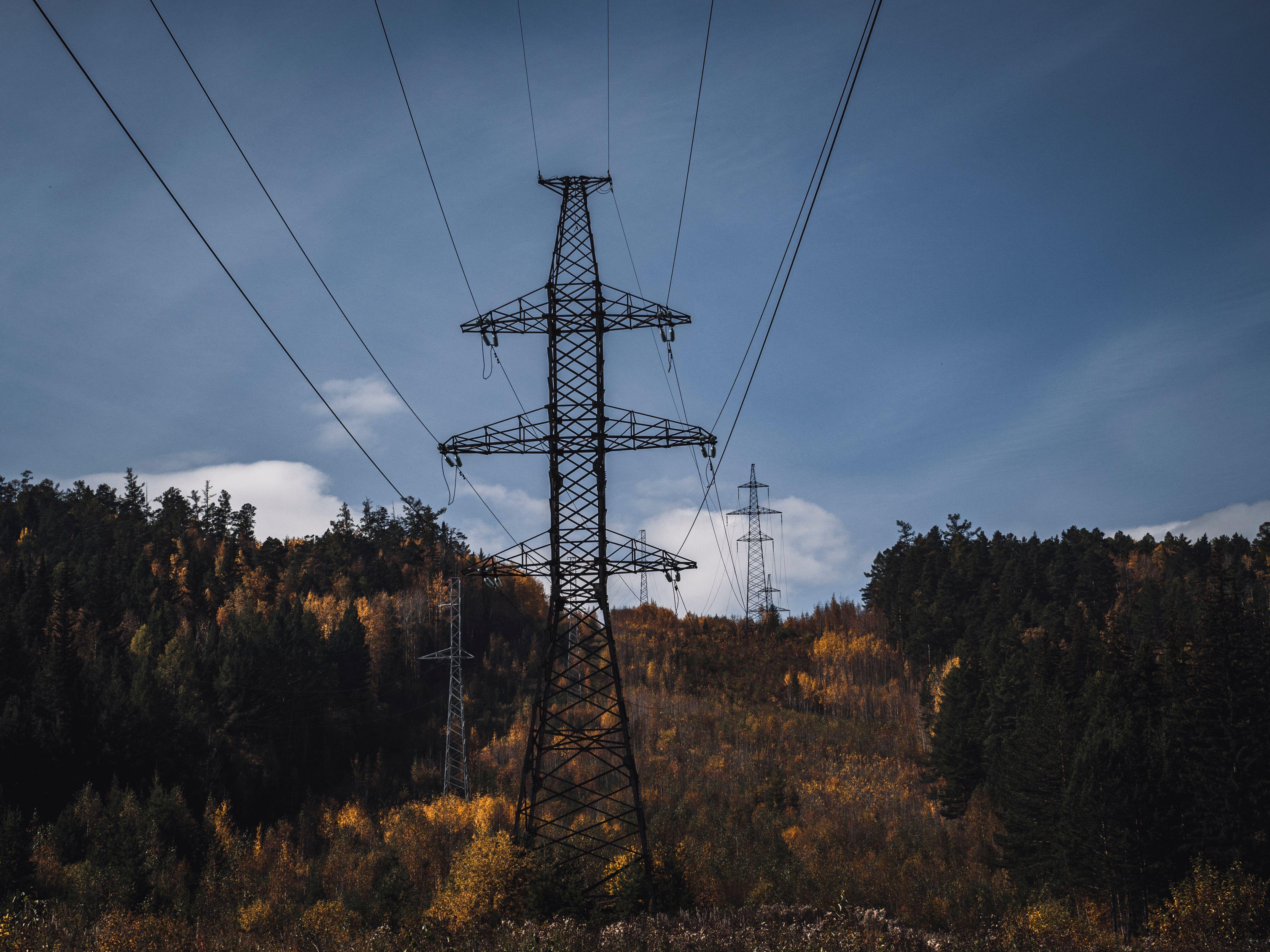 A picturesque autumn scene with transmission towers and colorful forest backdrop.
