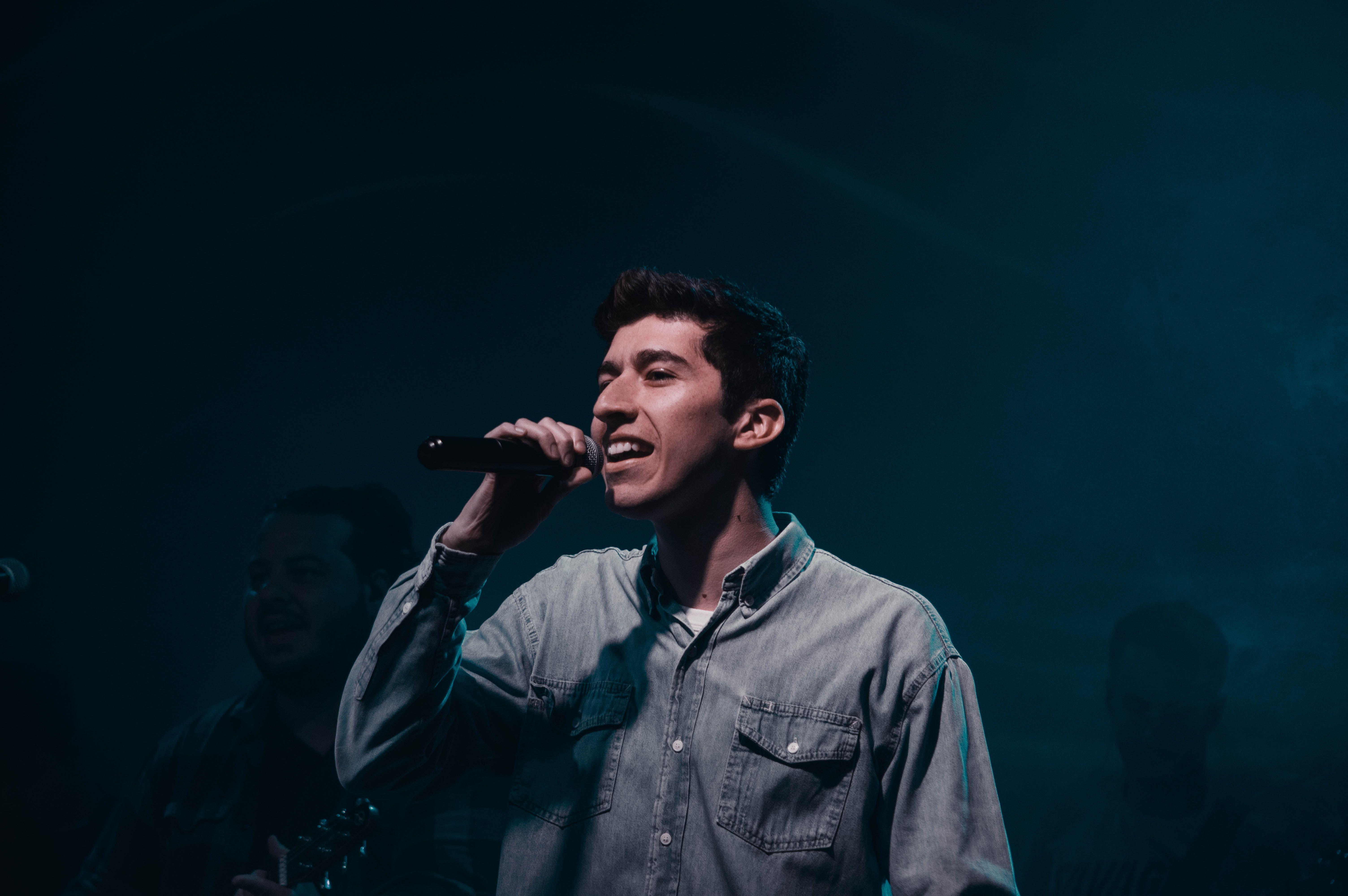 Young male singer performing passionately with microphone on stage. Captured in Mendoza, Argentina.