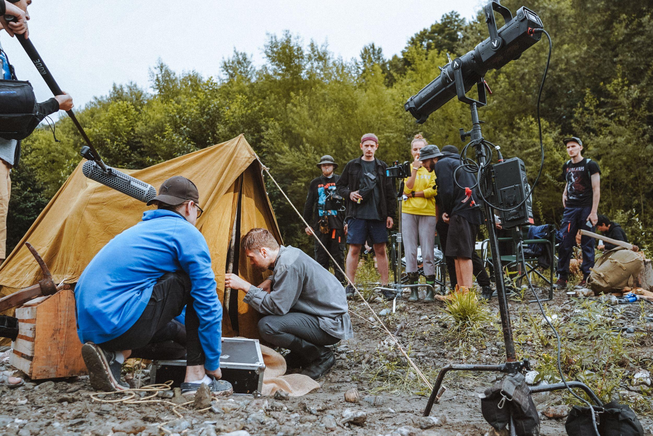Film crew setting up an outdoor scene with a tent and professional gear.