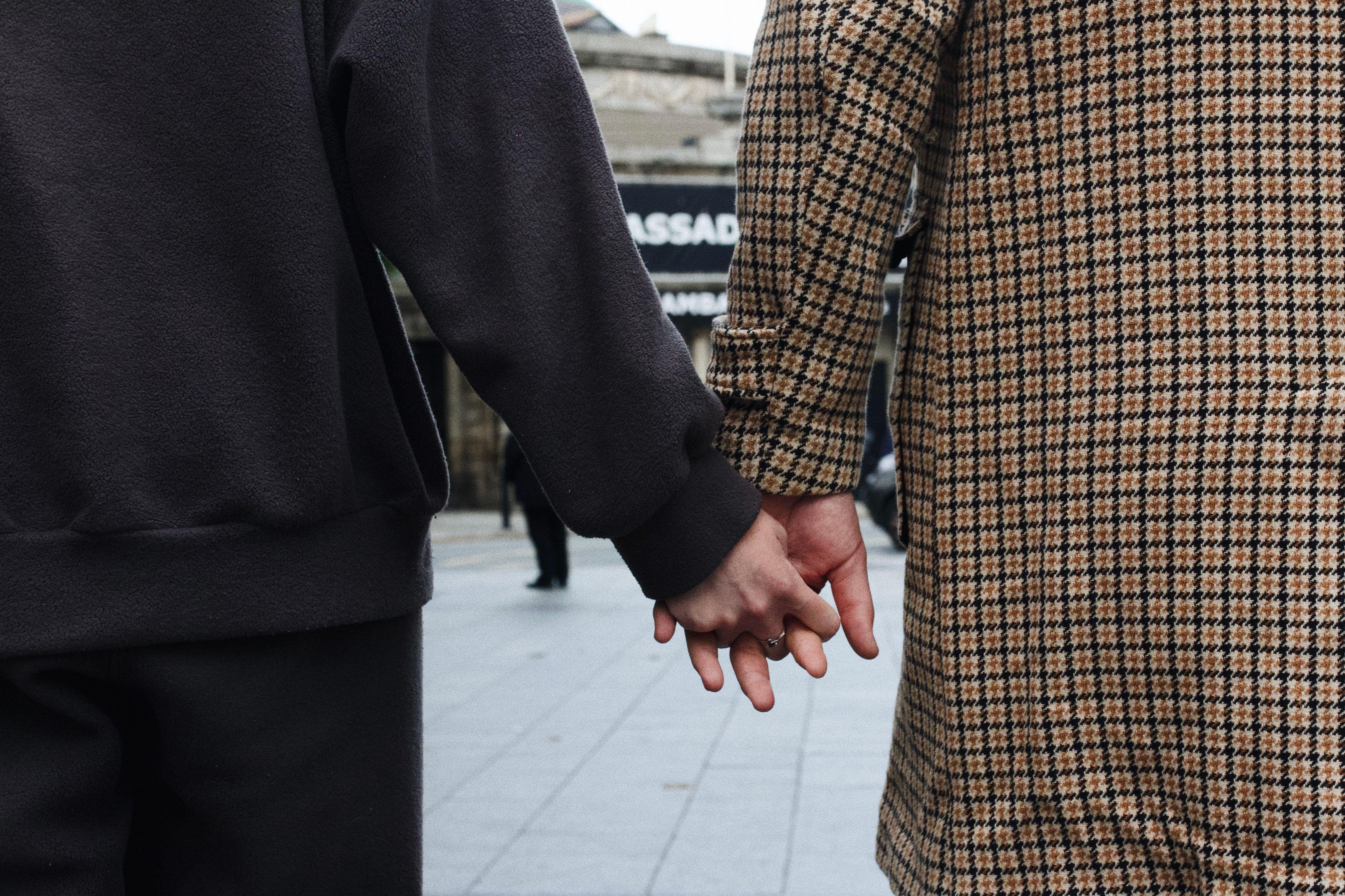 Close-up of a couple holding hands on a city street, signifying togetherness and connection.