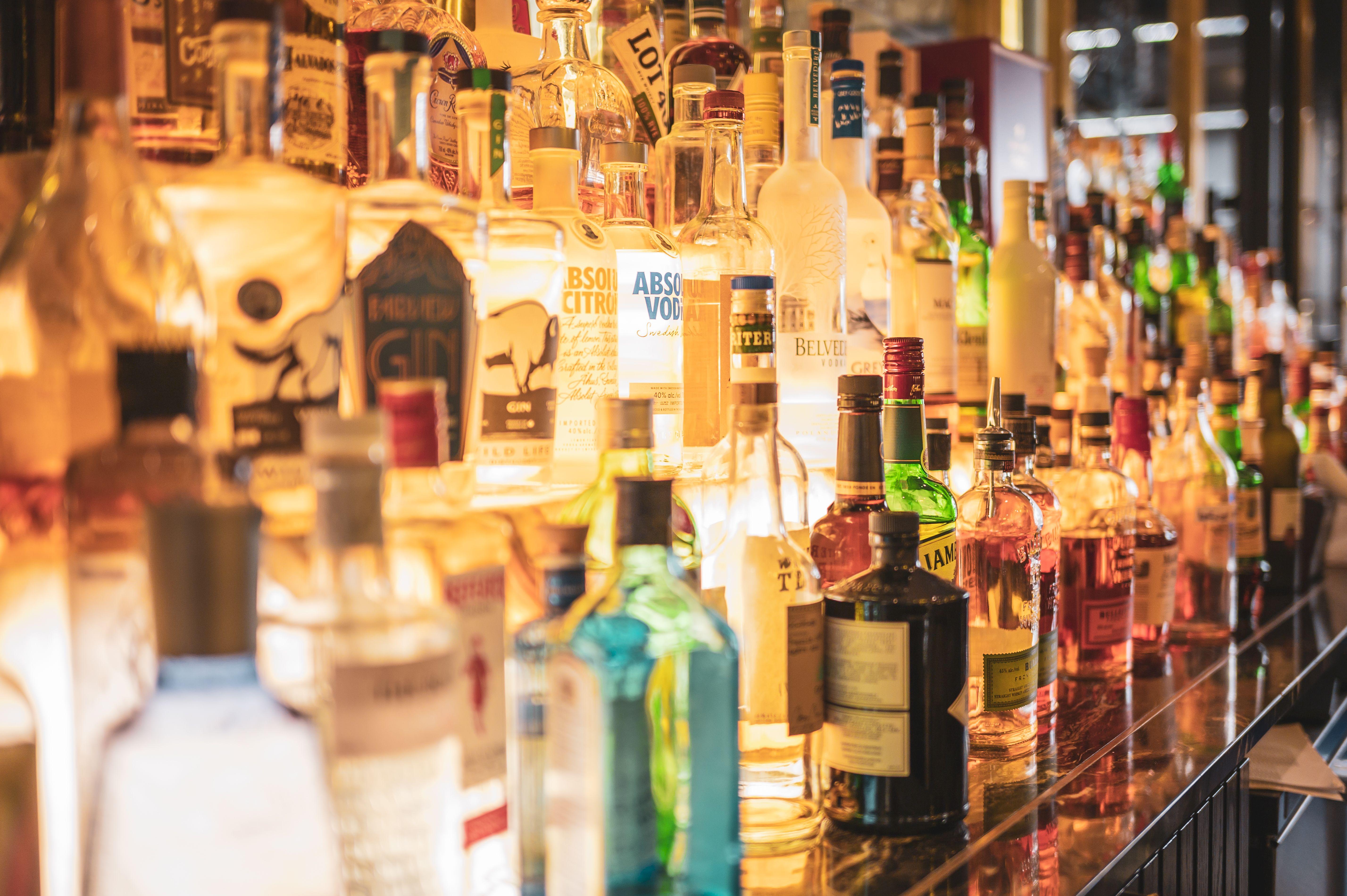 A close-up of various alcoholic beverage bottles displayed on a bar counter.