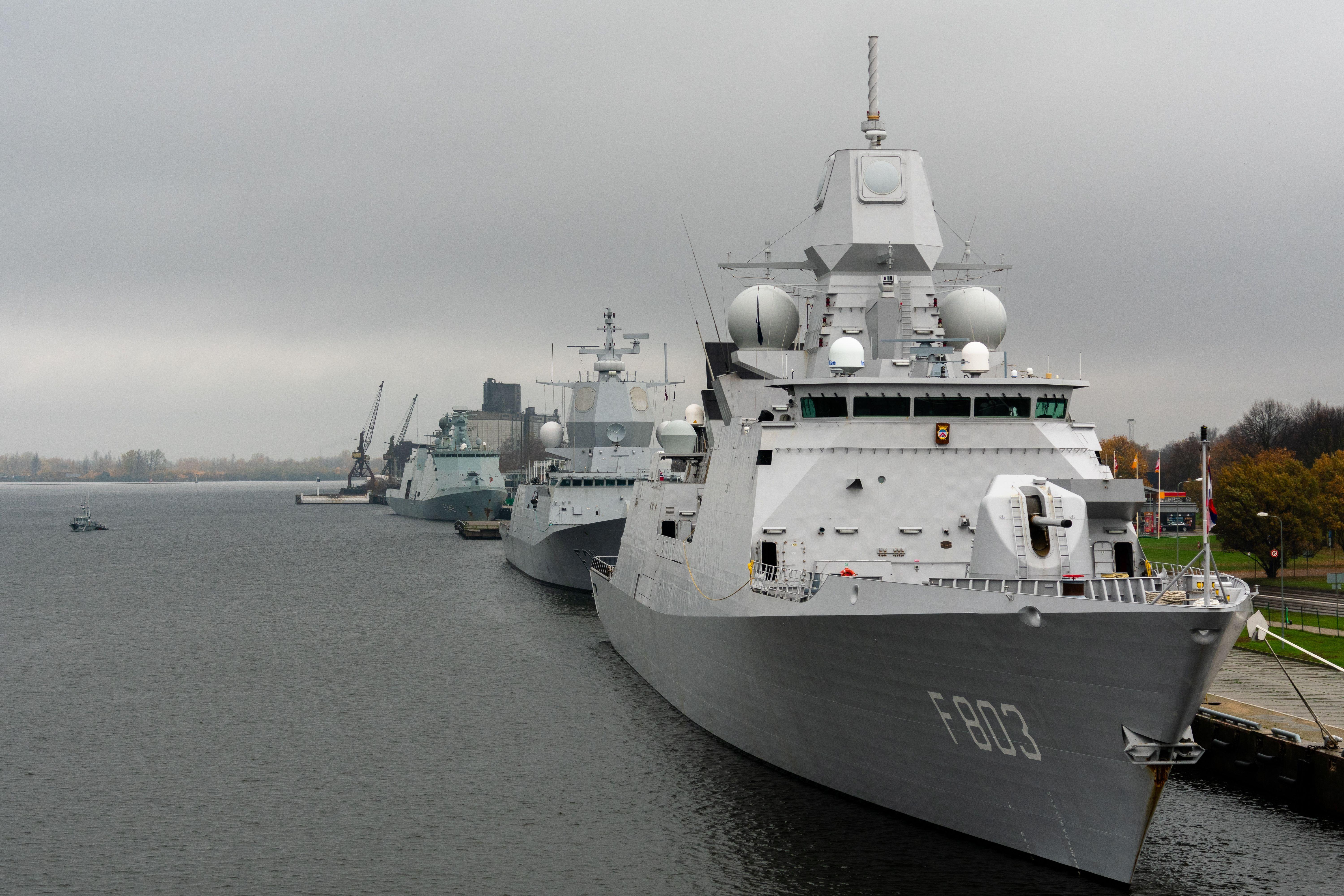 Moored warships at a harbor under cloudy skies, showcasing naval technology.