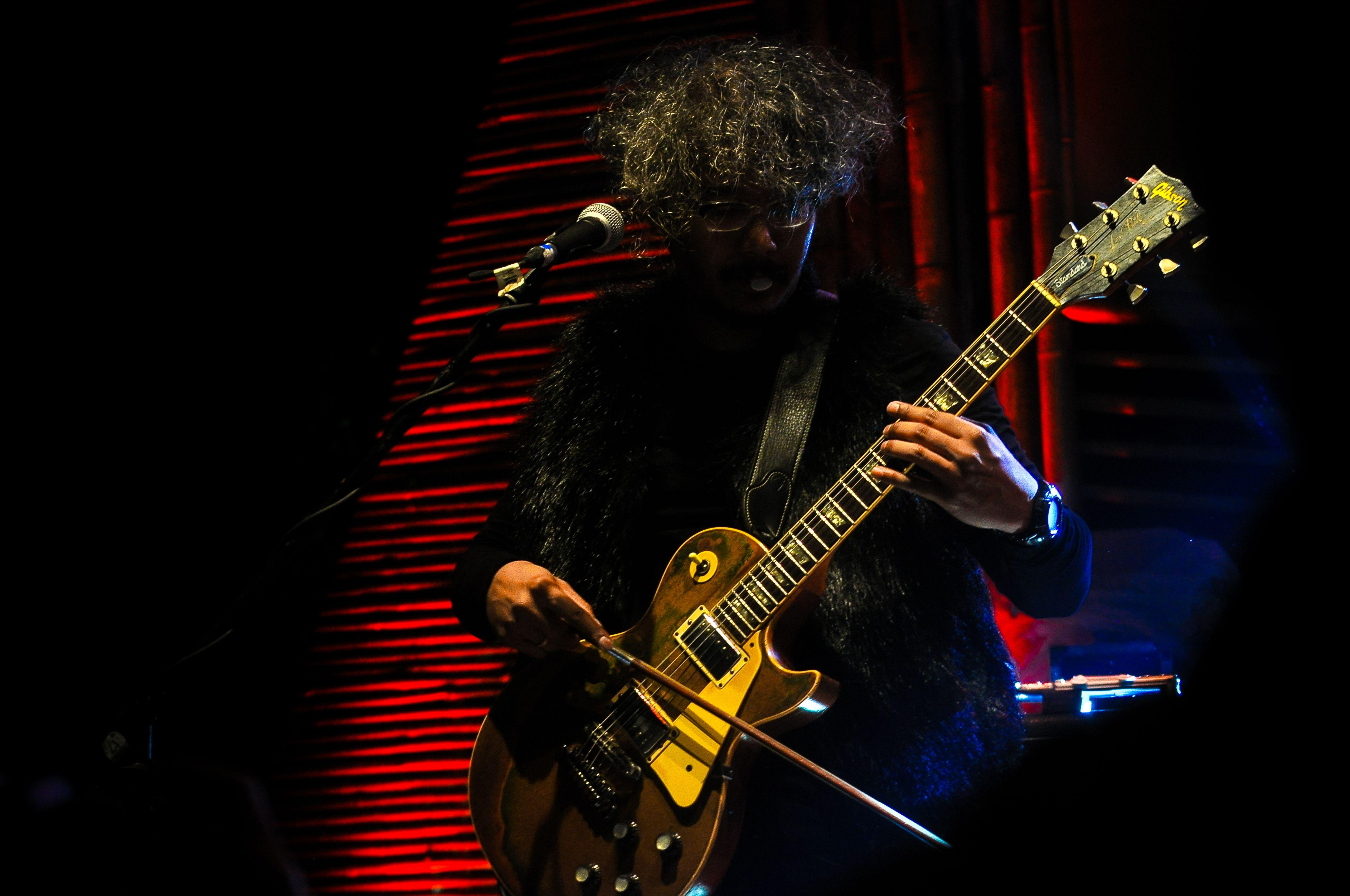 A musician passionately performing on stage with an electric guitar under dramatic lighting.