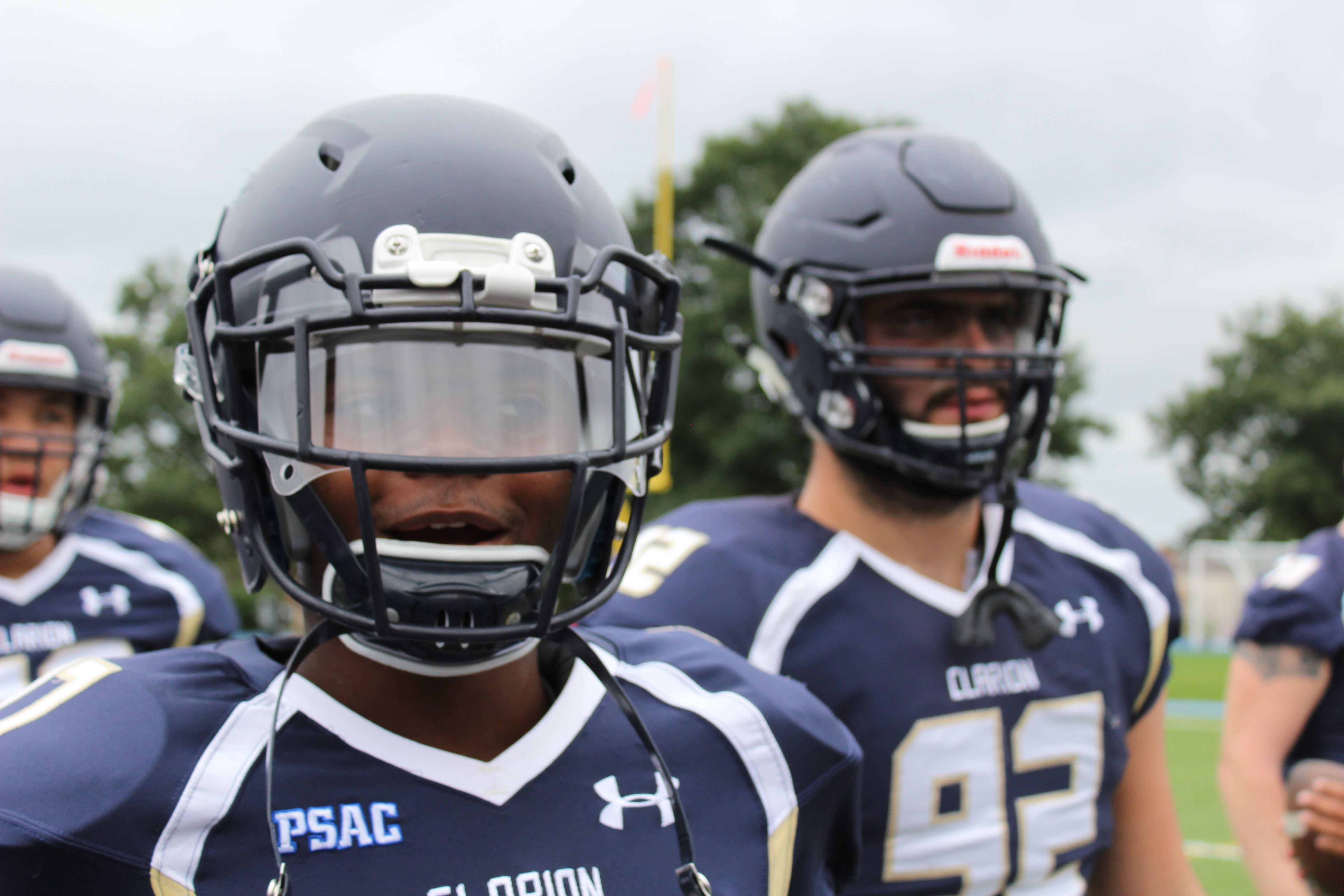 Close-up of American football players in action, wearing helmets and jerseys, showcasing team spirit.