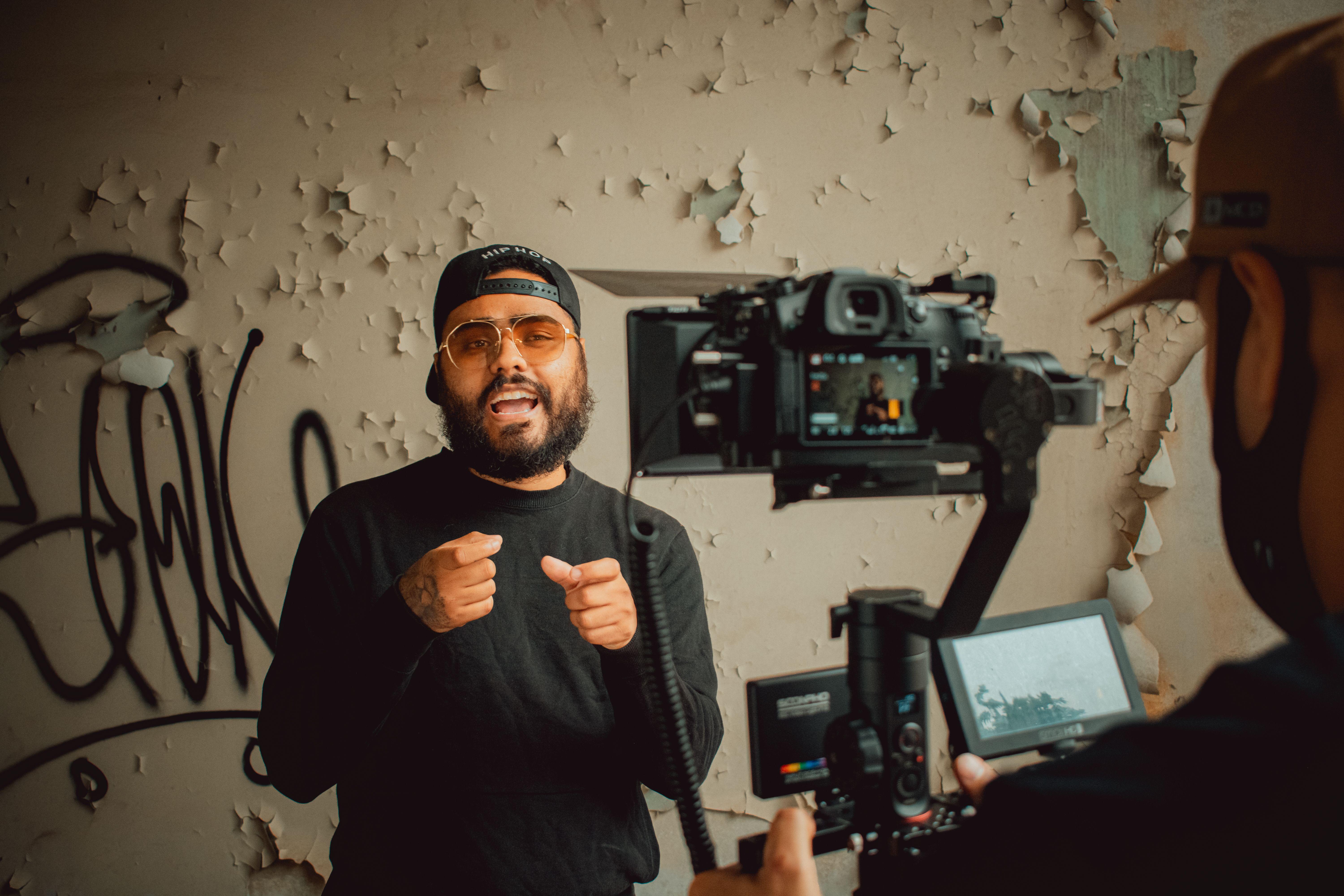 Hip-hop artist passionately performing during an indoor music video recording session.