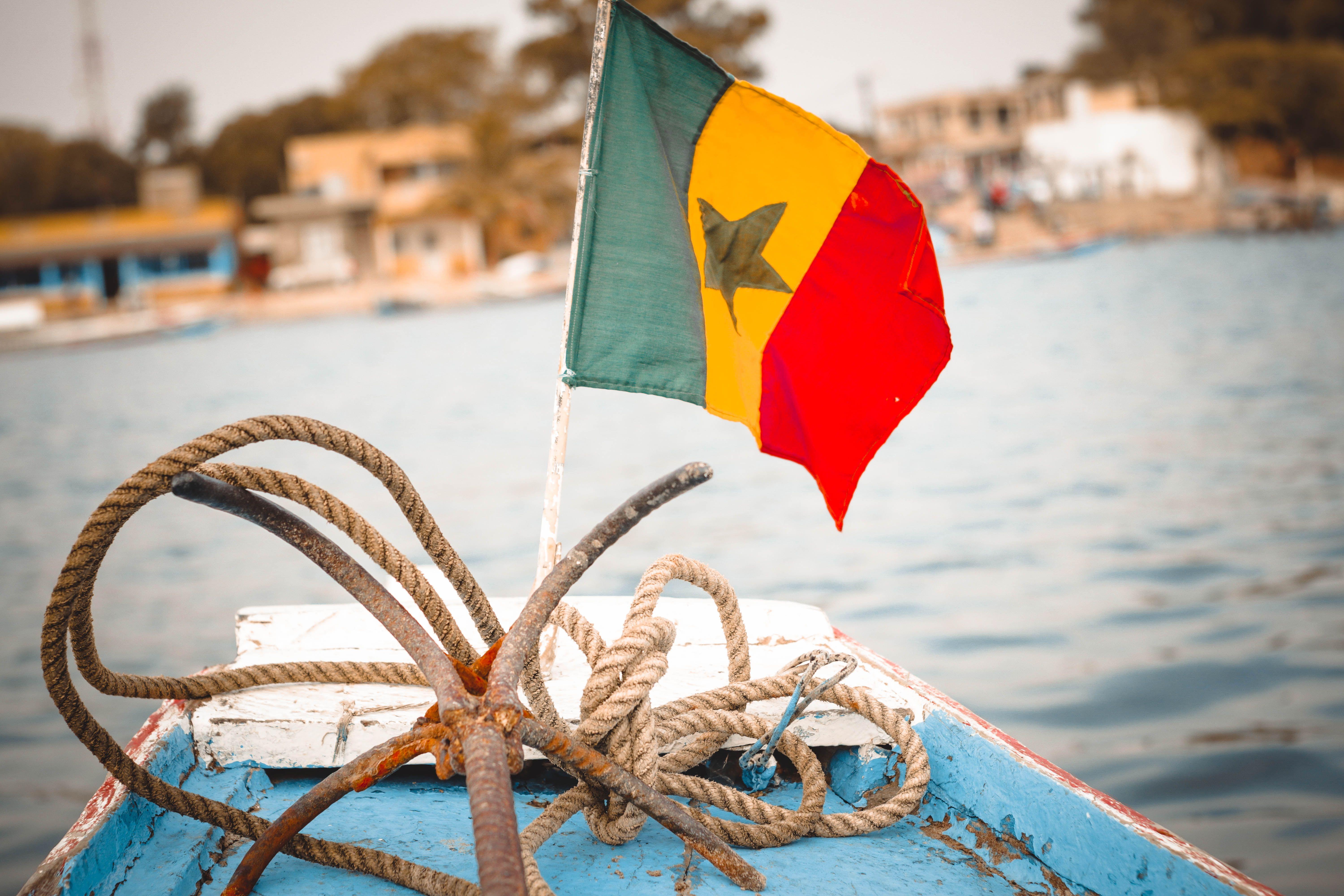 Colorful Senegalese flag and nautical ropes on a boat deck, perfect for travel themes.