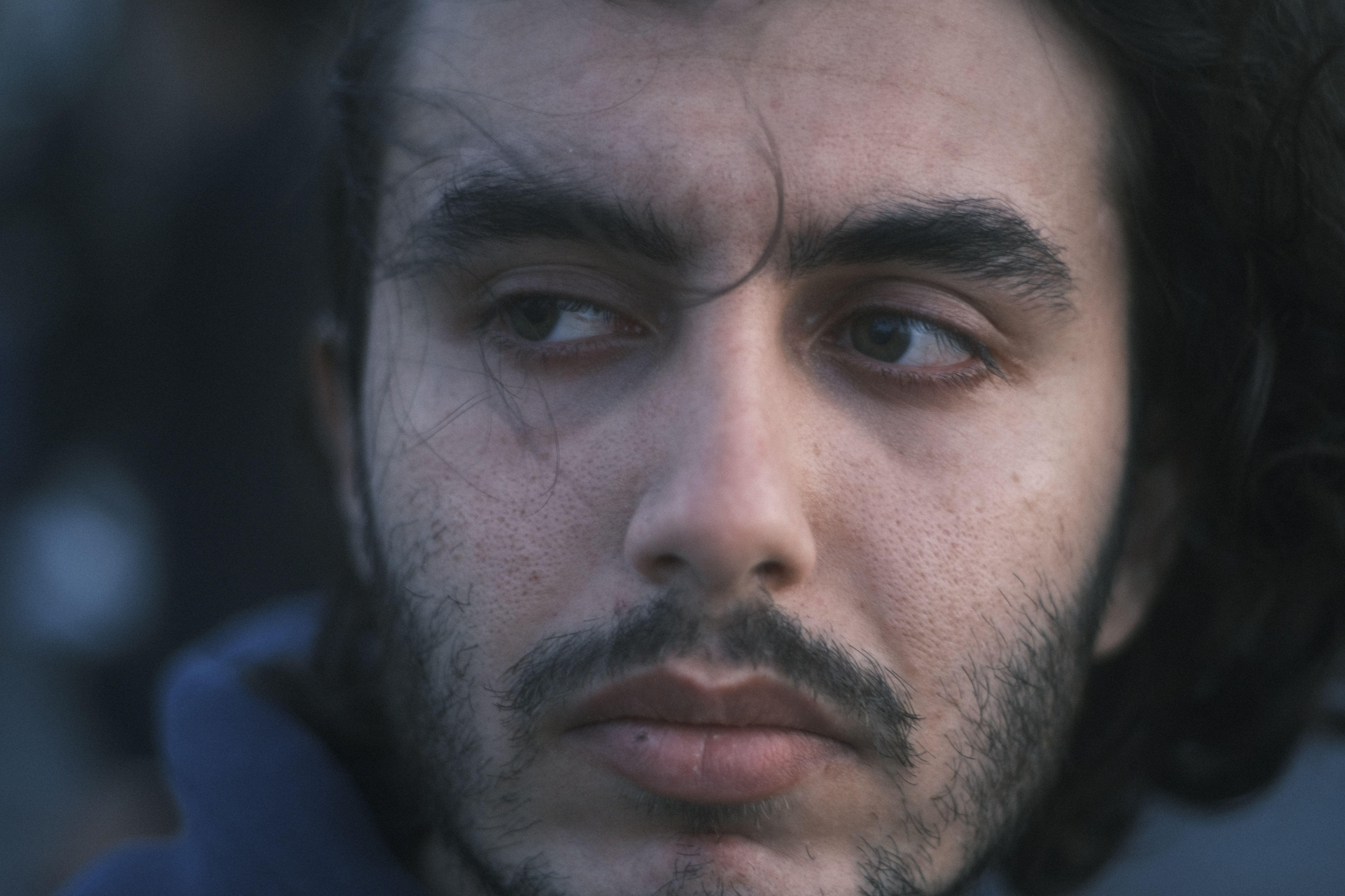 Close-up portrait of a man gazing sideways with a contemplative expression.