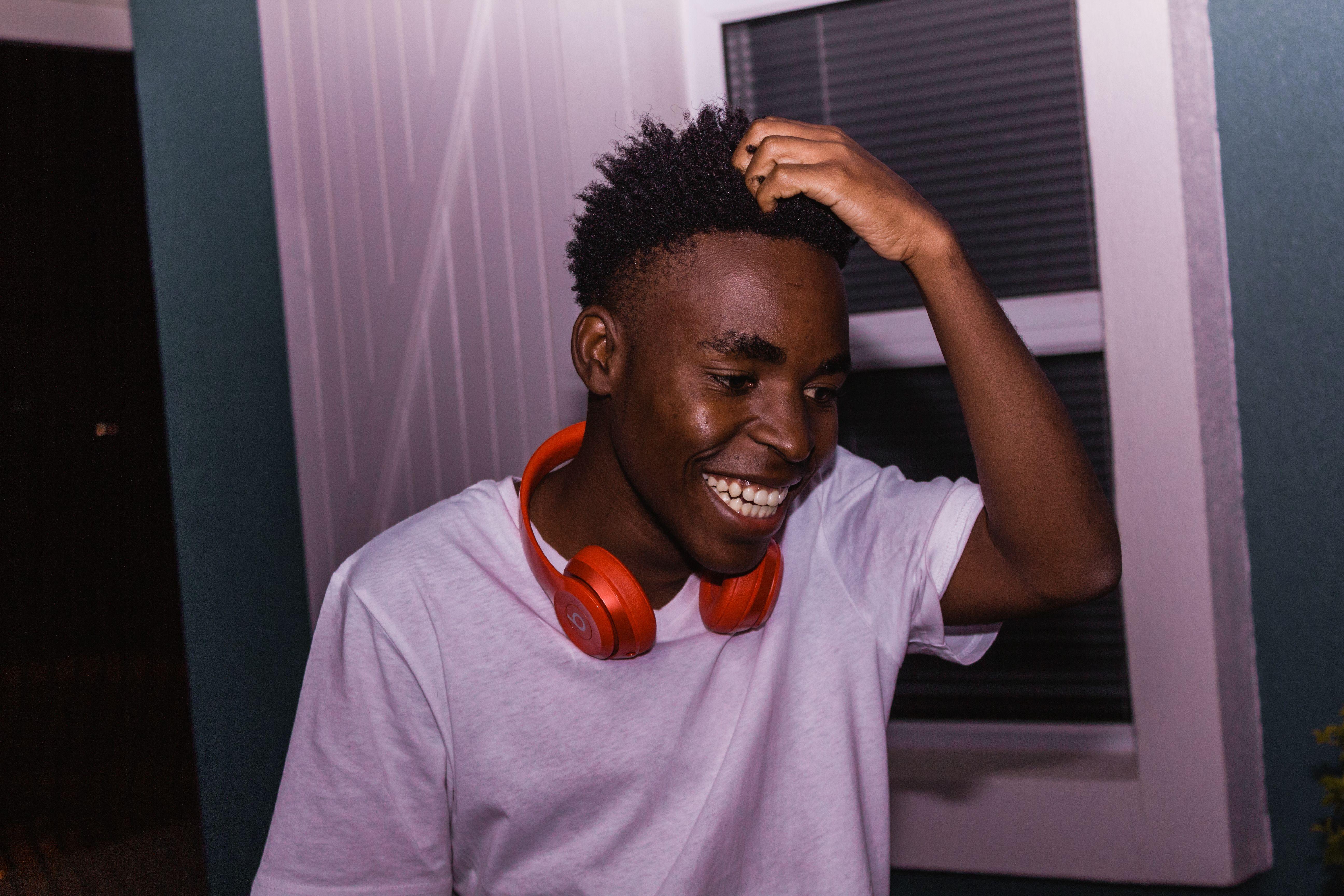 A cheerful young man wearing headphones, smiling indoors, exuding joy and happiness.