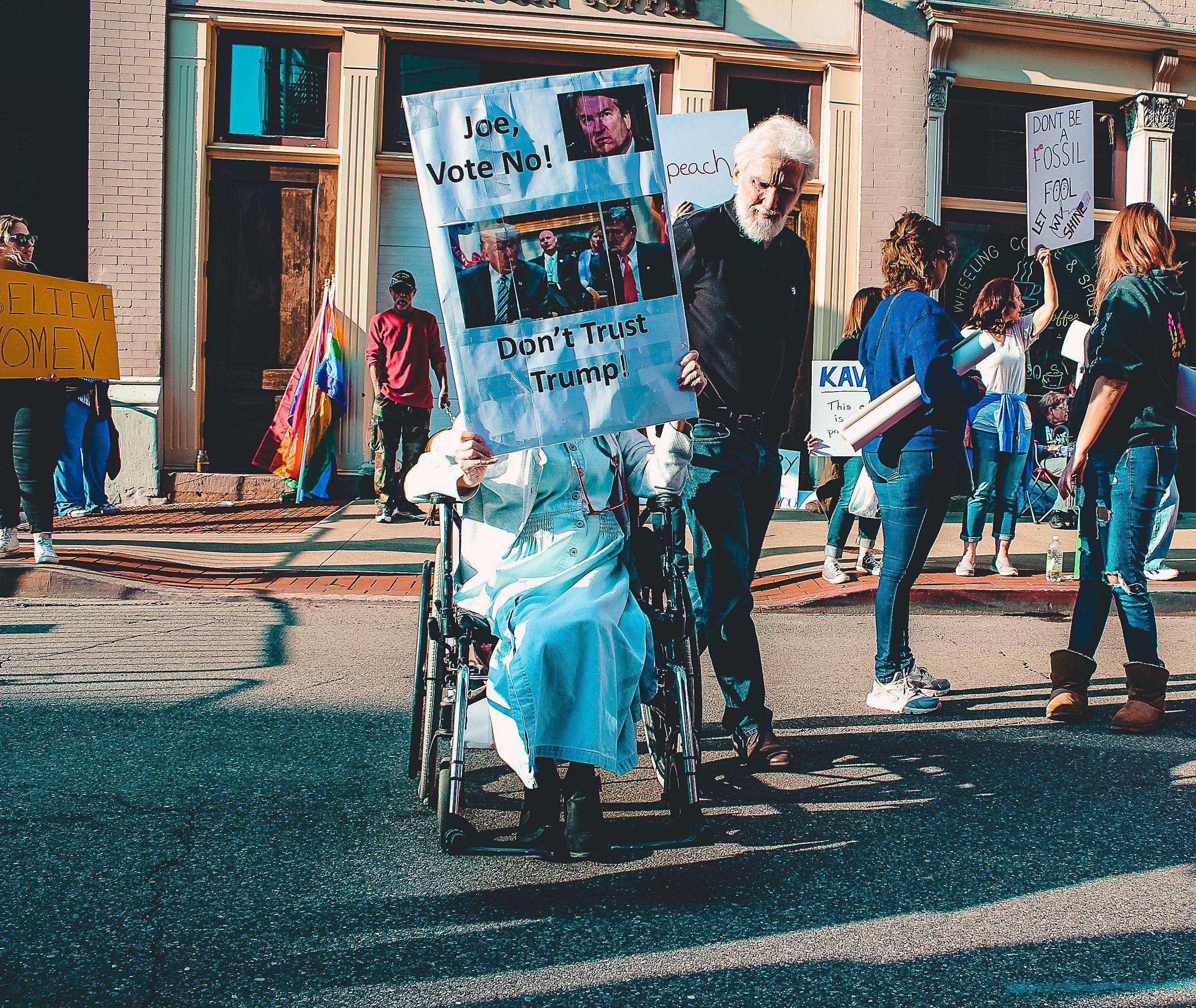 A diverse group of people protesting outdoors with signs and banners in a vibrant street scene.