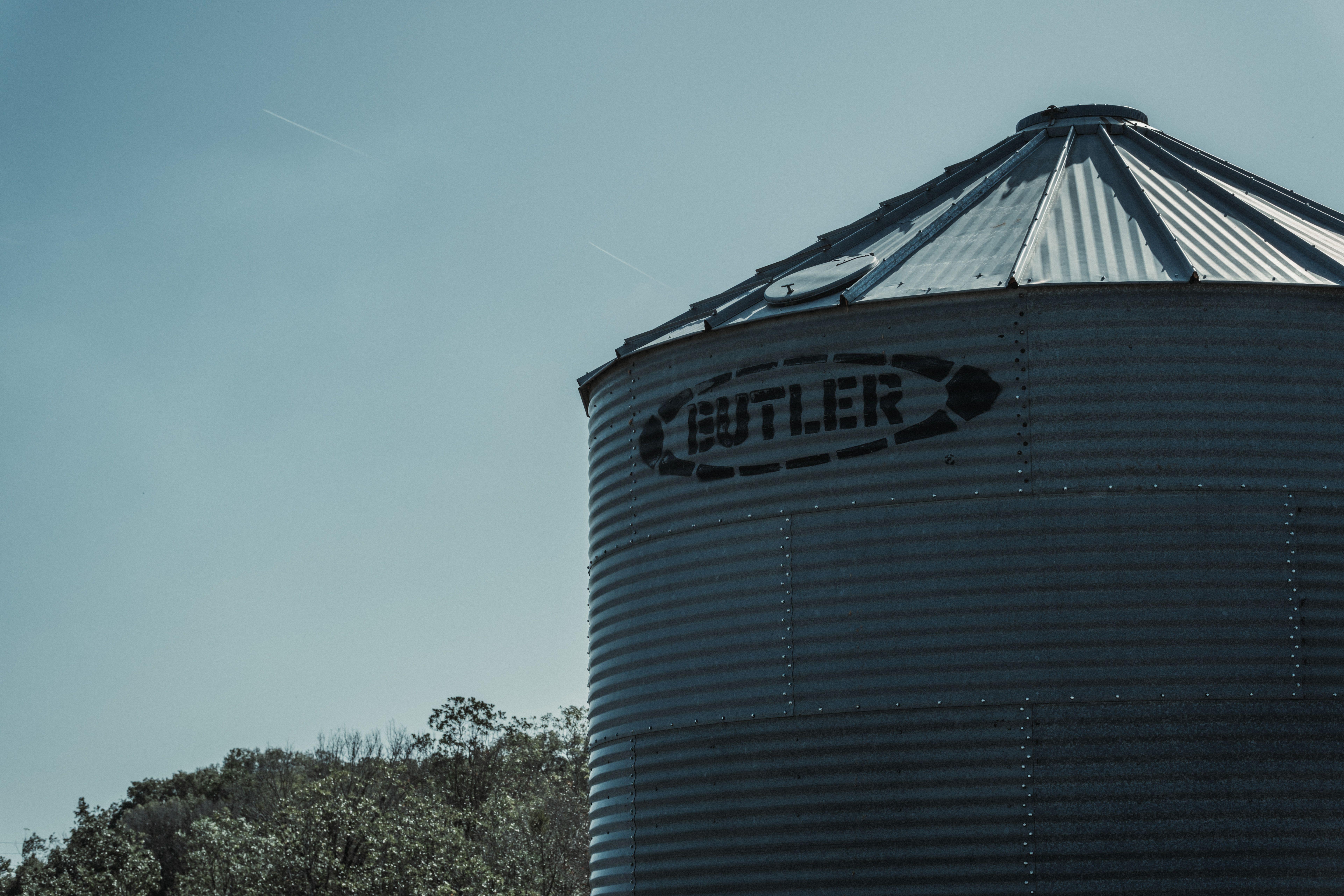 Silhouette of a corrugated metal grain bin against the sky, highlighting rural storage facilities.