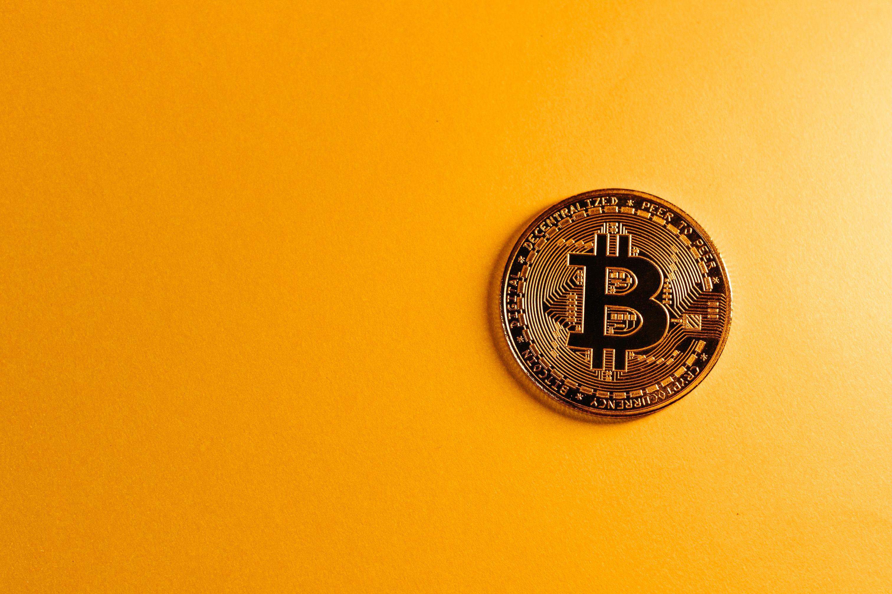 Close-up of a Bitcoin cryptocurrency coin on a vibrant yellow background, symbolizing digital money.