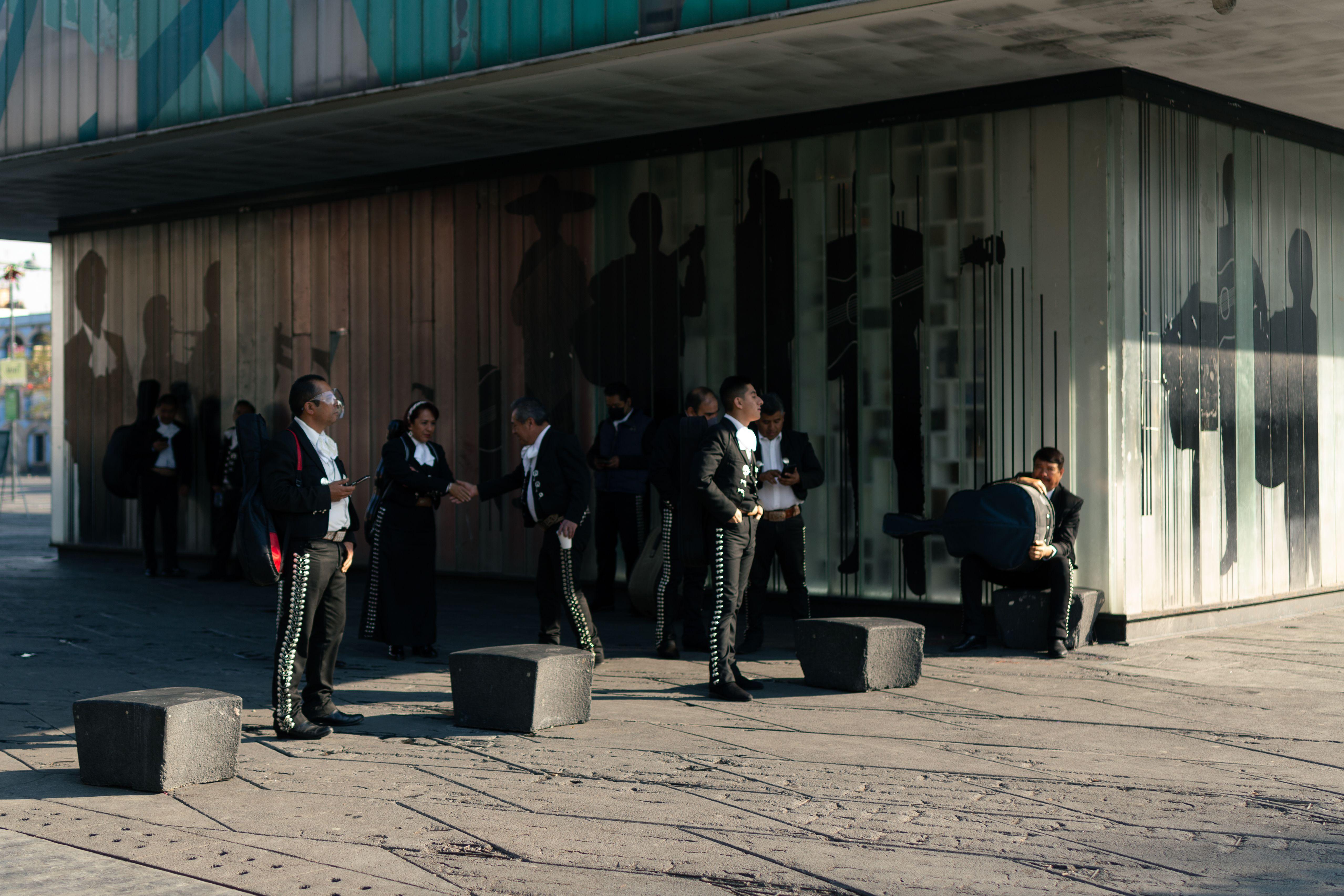 A mariachi band wearing traditional outfits performs in a city street, capturing vibrant culture.