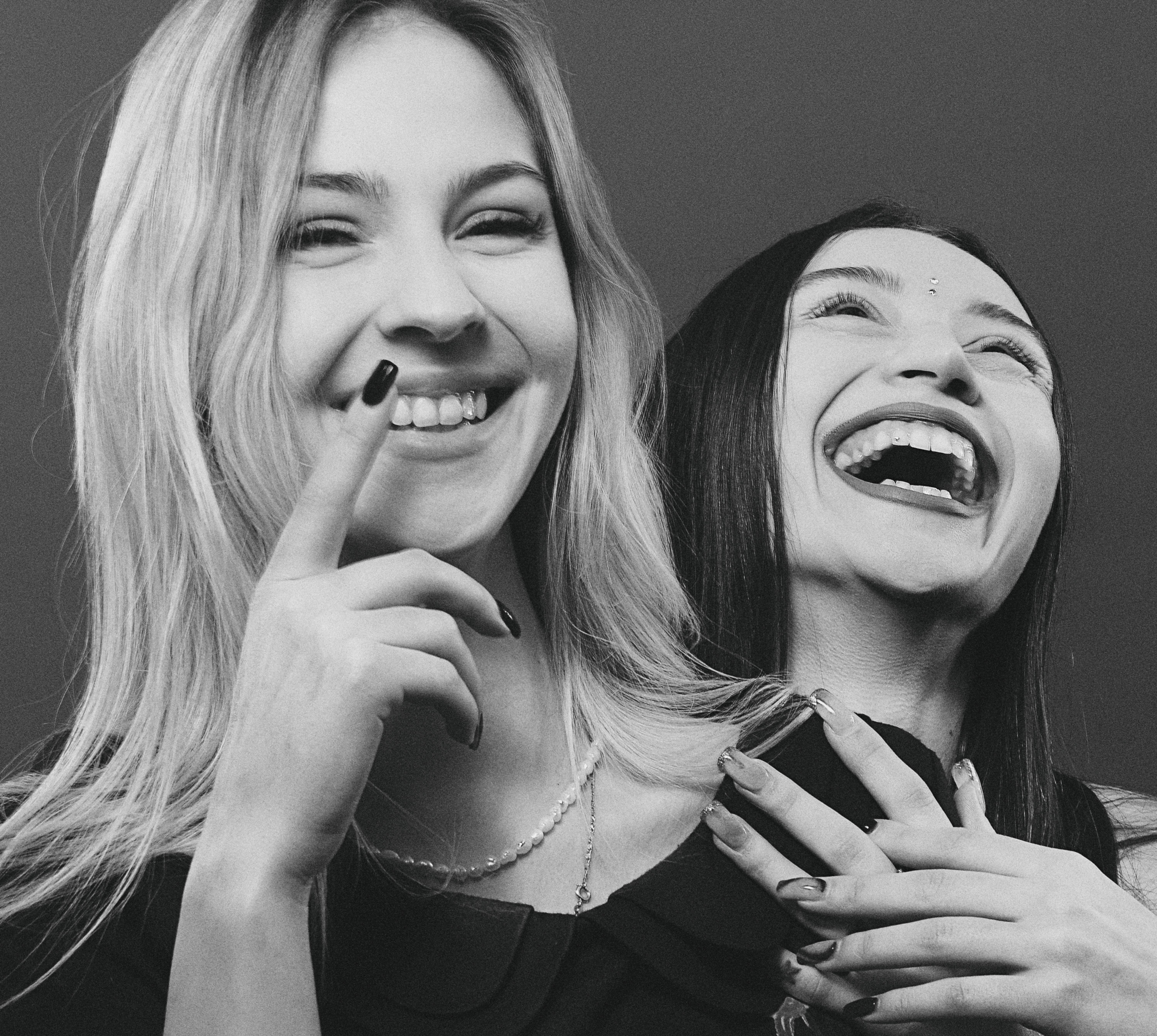Black and white portrait of two women laughing joyfully, expressing friendship.