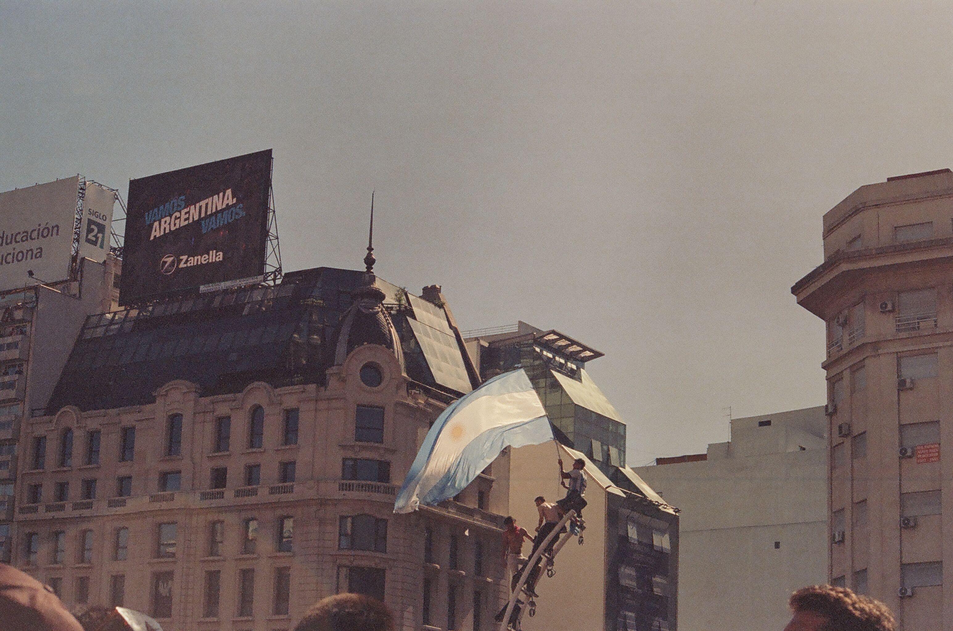 Crowd celebrating in Buenos Aires with Argentine flags, capturing urban excitement.