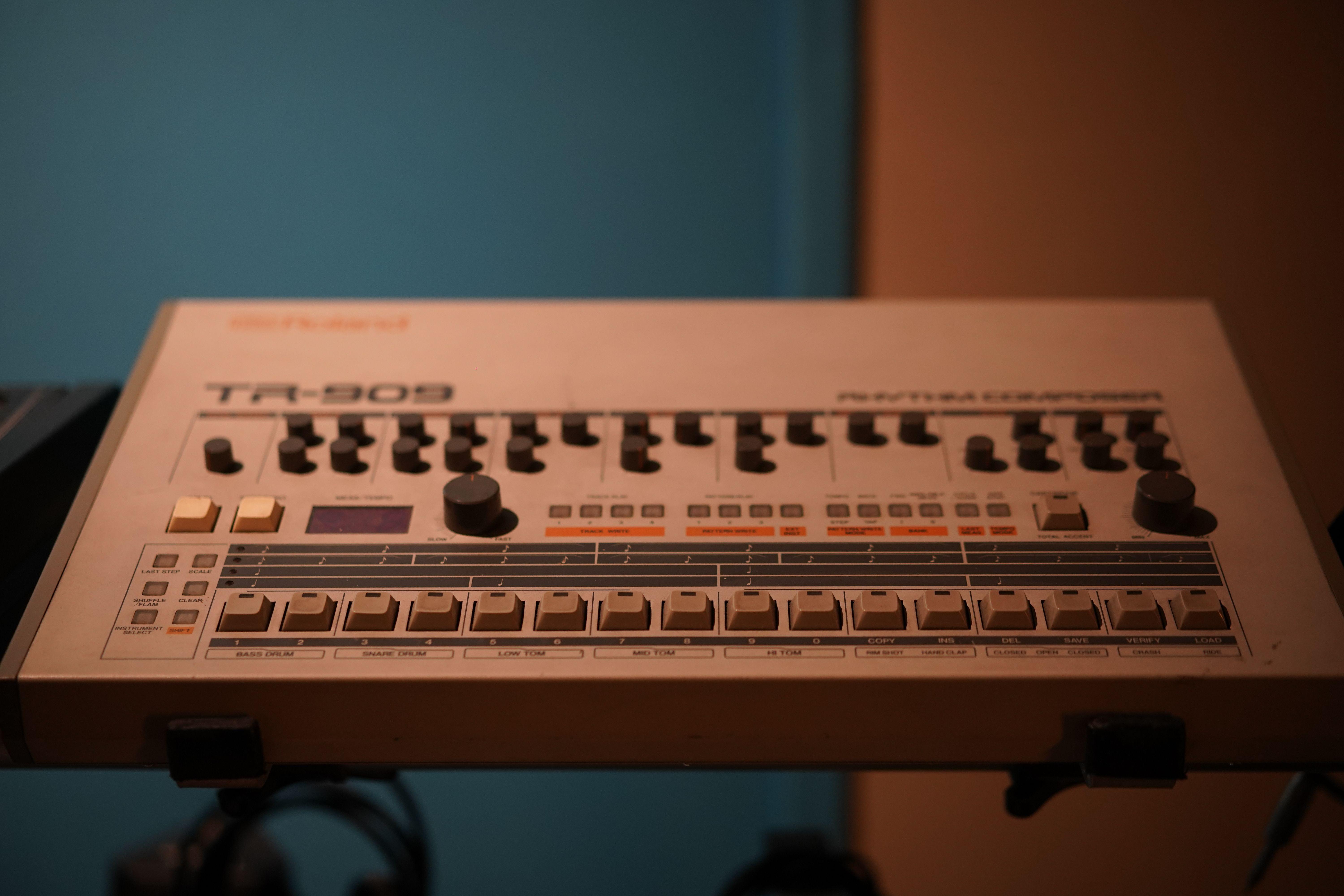 Close-up of a classic Roland TR-909 drum machine in a studio setting.