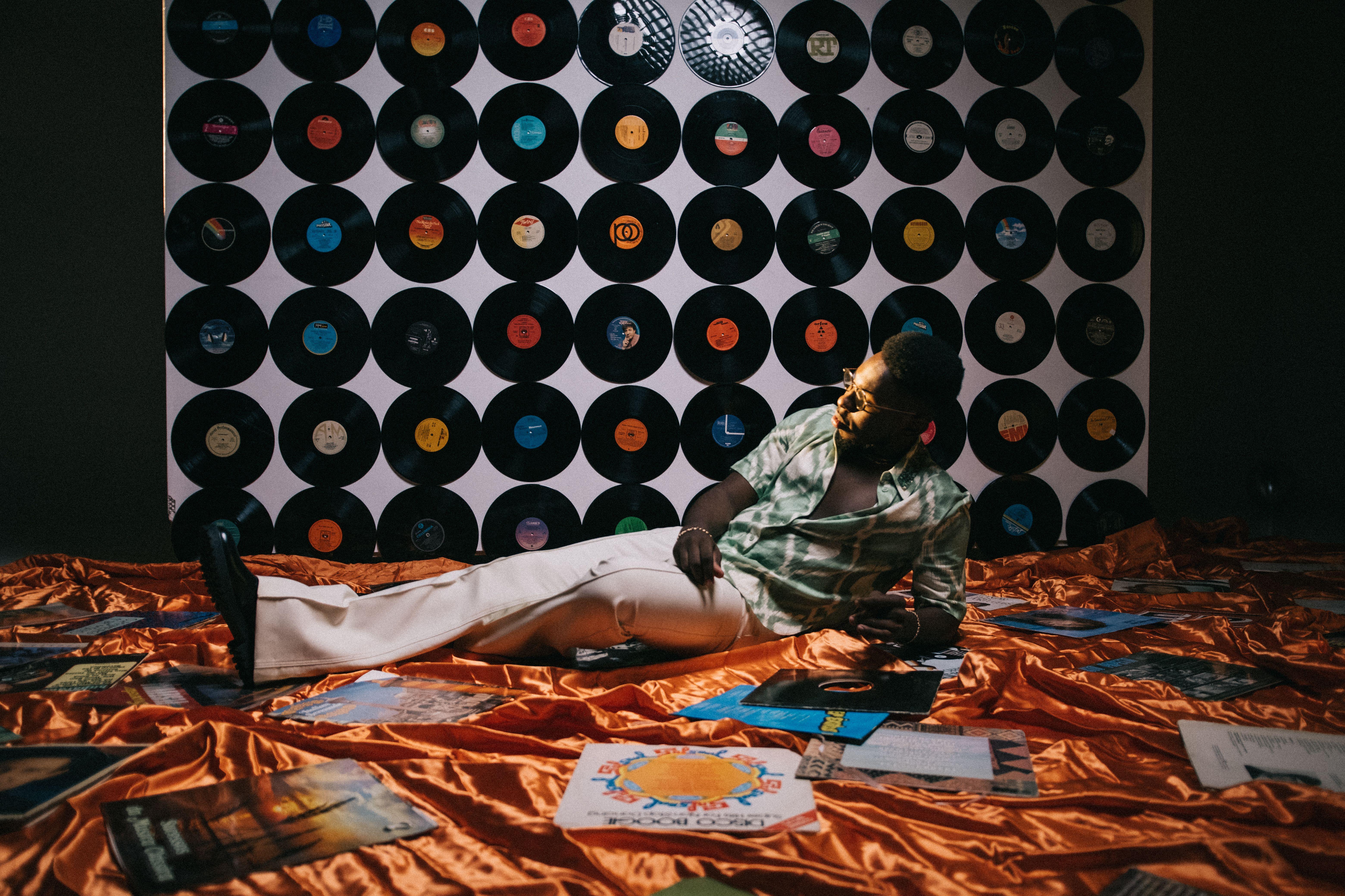 A stylish man lounges amidst vinyl records, evoking a retro and vintage atmosphere.